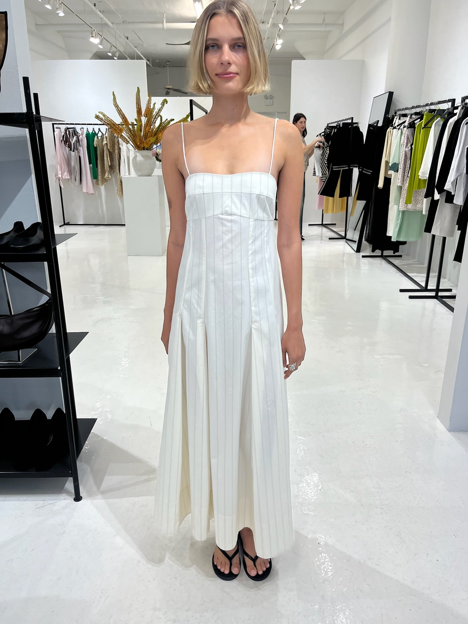 Woman wearing the st. agni everyday cotton pleated dress in ecru stripe standing