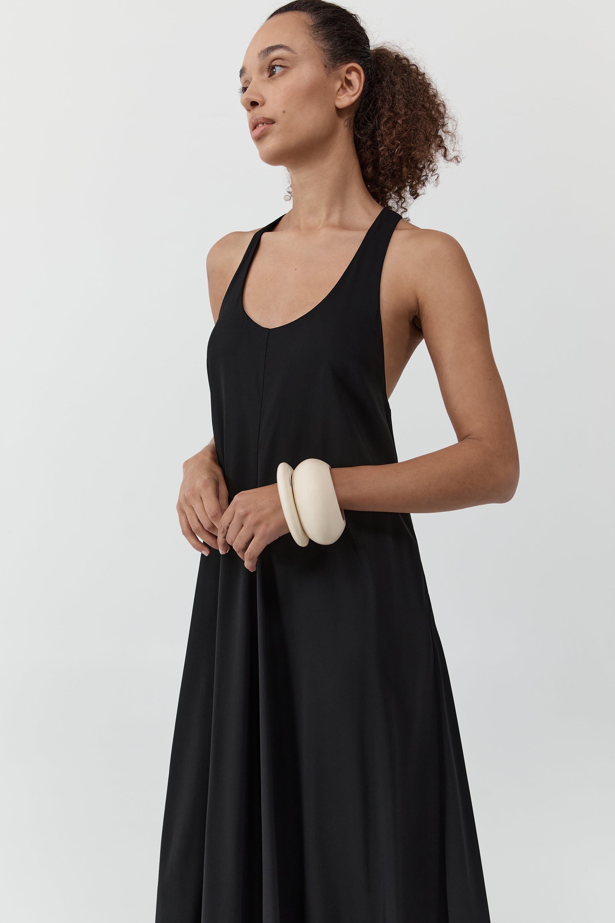Woman wearing the st. agni fluid tank dress standing in front of a cream background