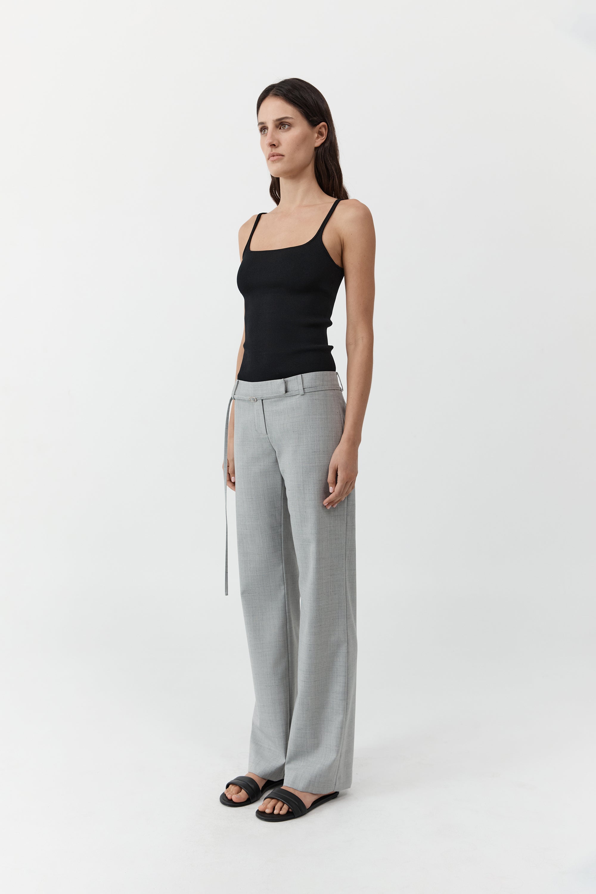 Woman wearing the st. agni slim square neck top In black with gray trousers in front of a cream background