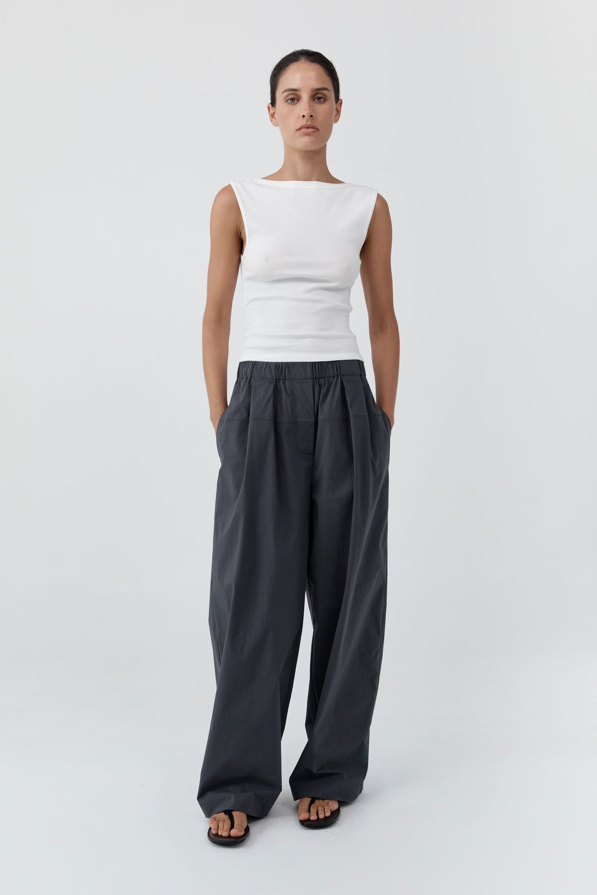 Woman wearing the St Agni Organic Cotton Ballerina Top-White and gray pants standing against a white background