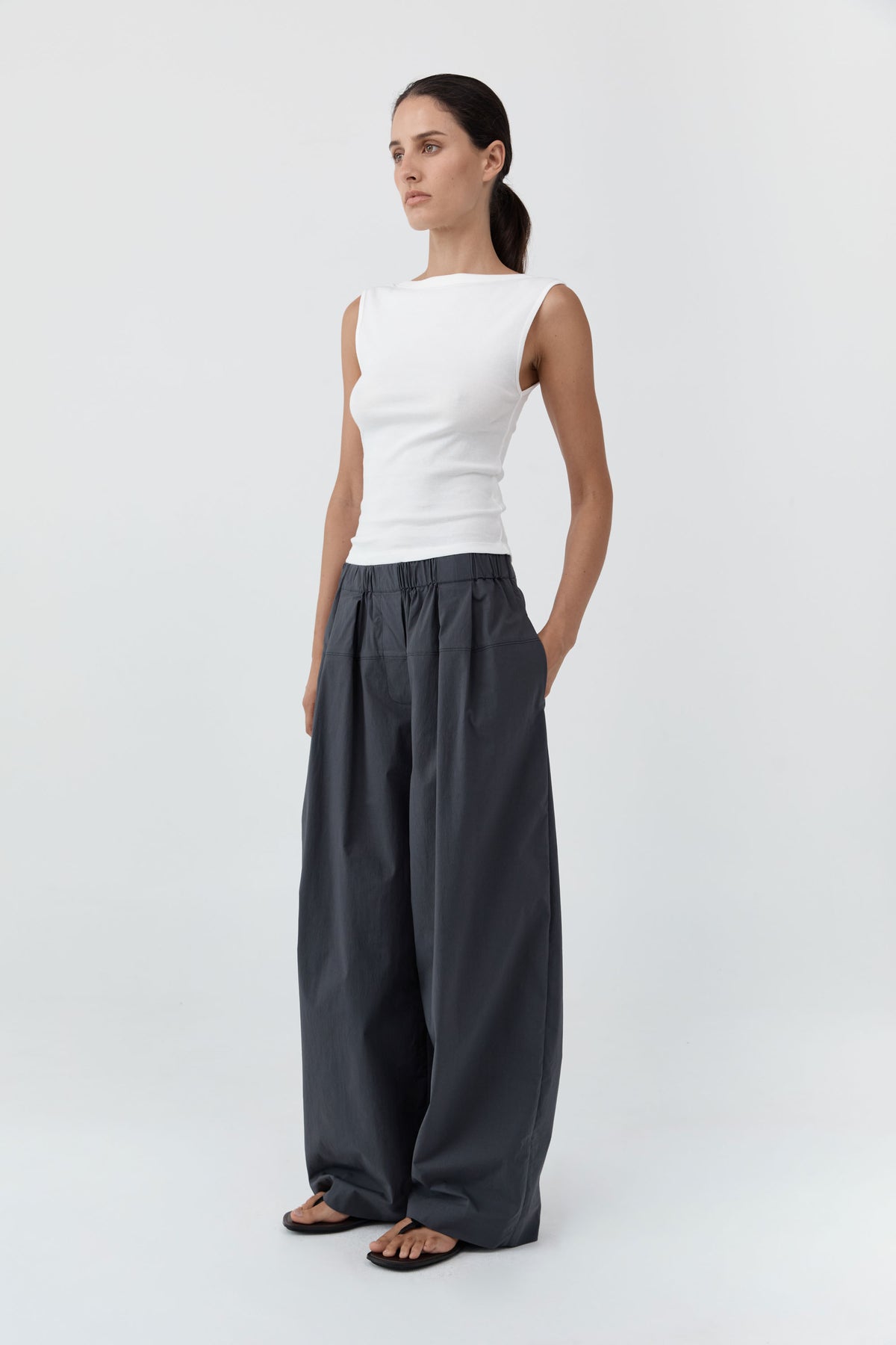 Woman wearing the St Agni Organic Cotton Ballerina Top-White and gray pants standing against a white background