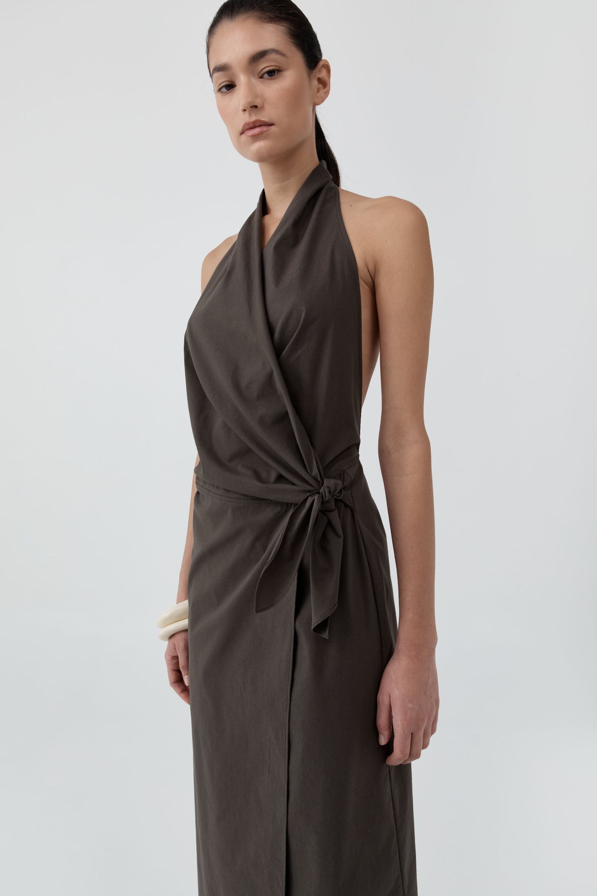 Close up of a woman wearing St Agni Halter Wrap Backless Dress standing against a white background