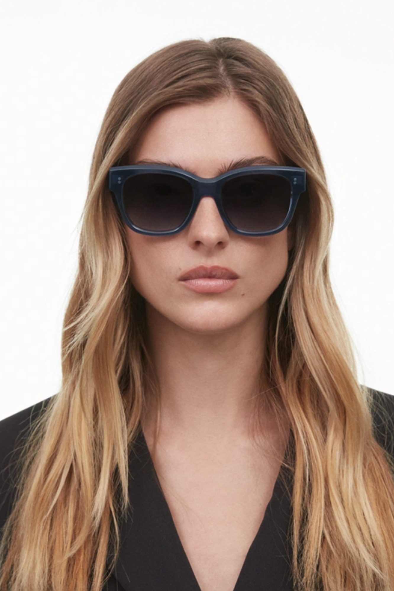 Woman wearing dark sunglasses with a plain background