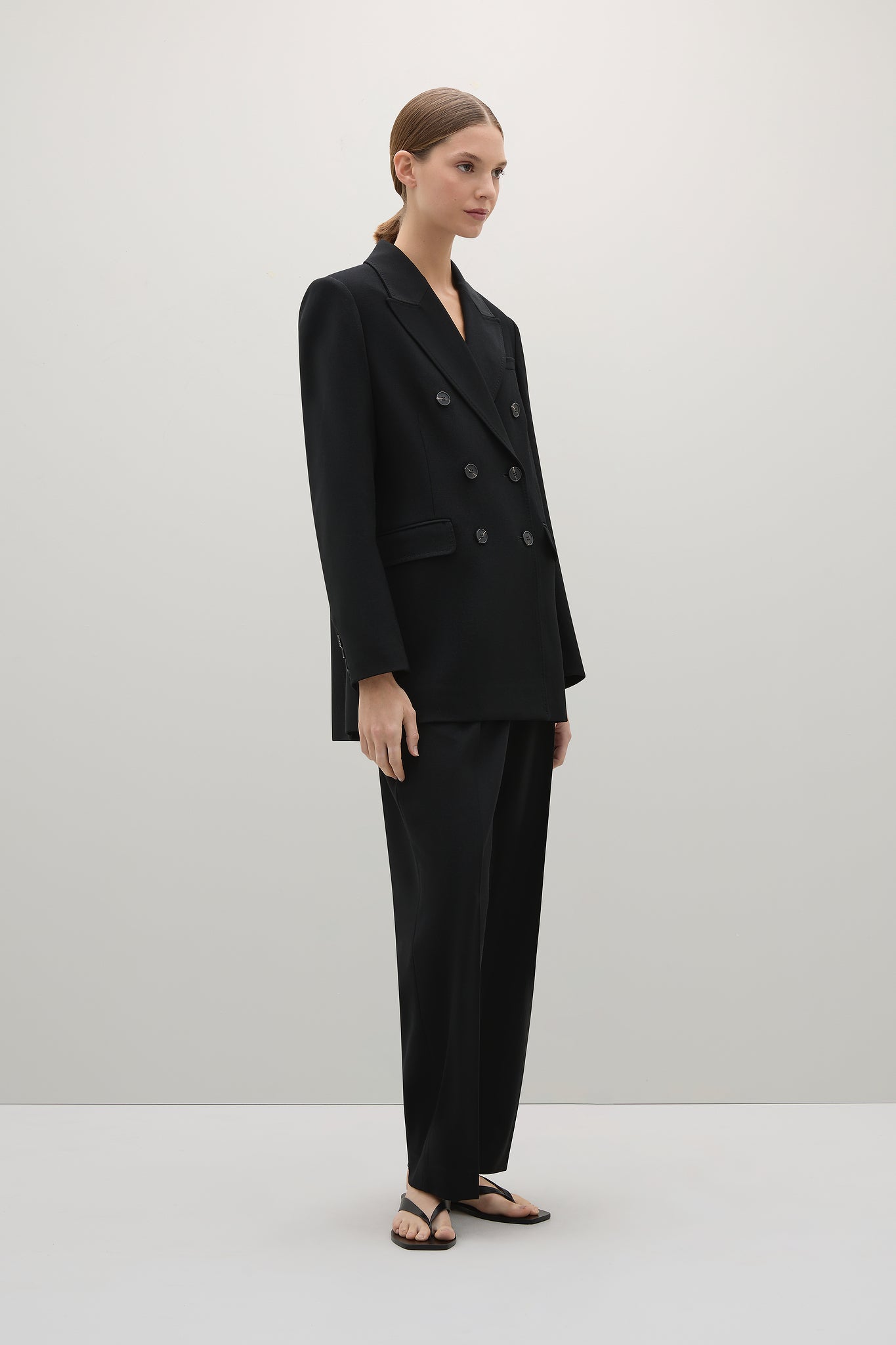 Woman wearing a black suit standing against a white background
