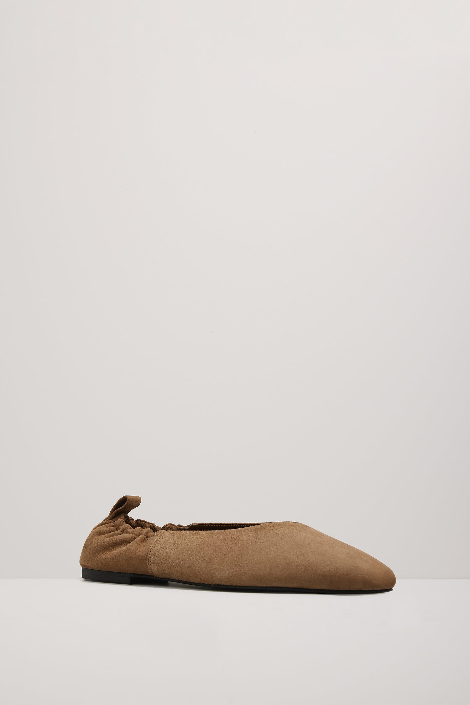 Brown suede flat shoe on a light gray background