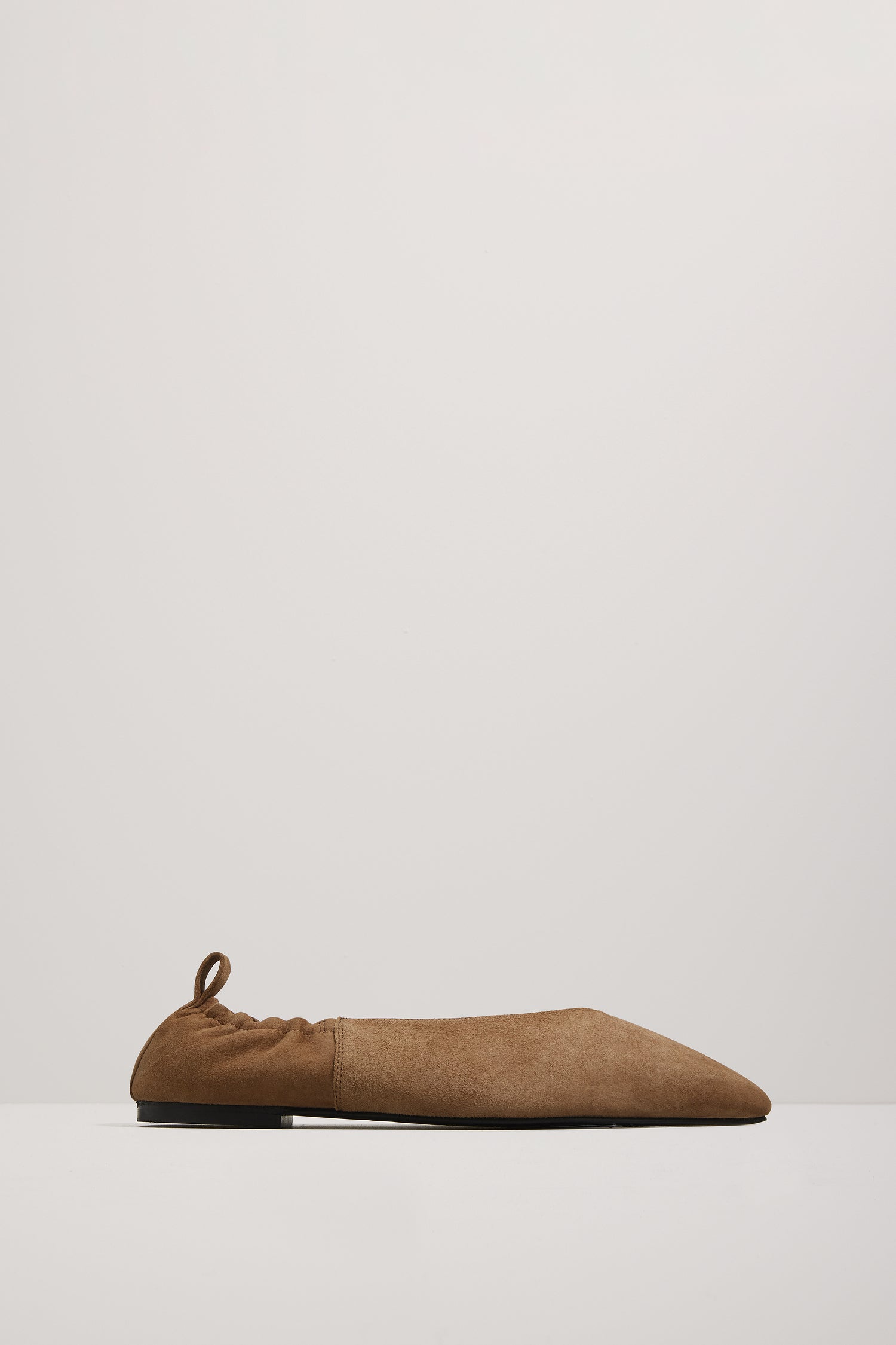 Brown suede slip-on shoe on a light gray background