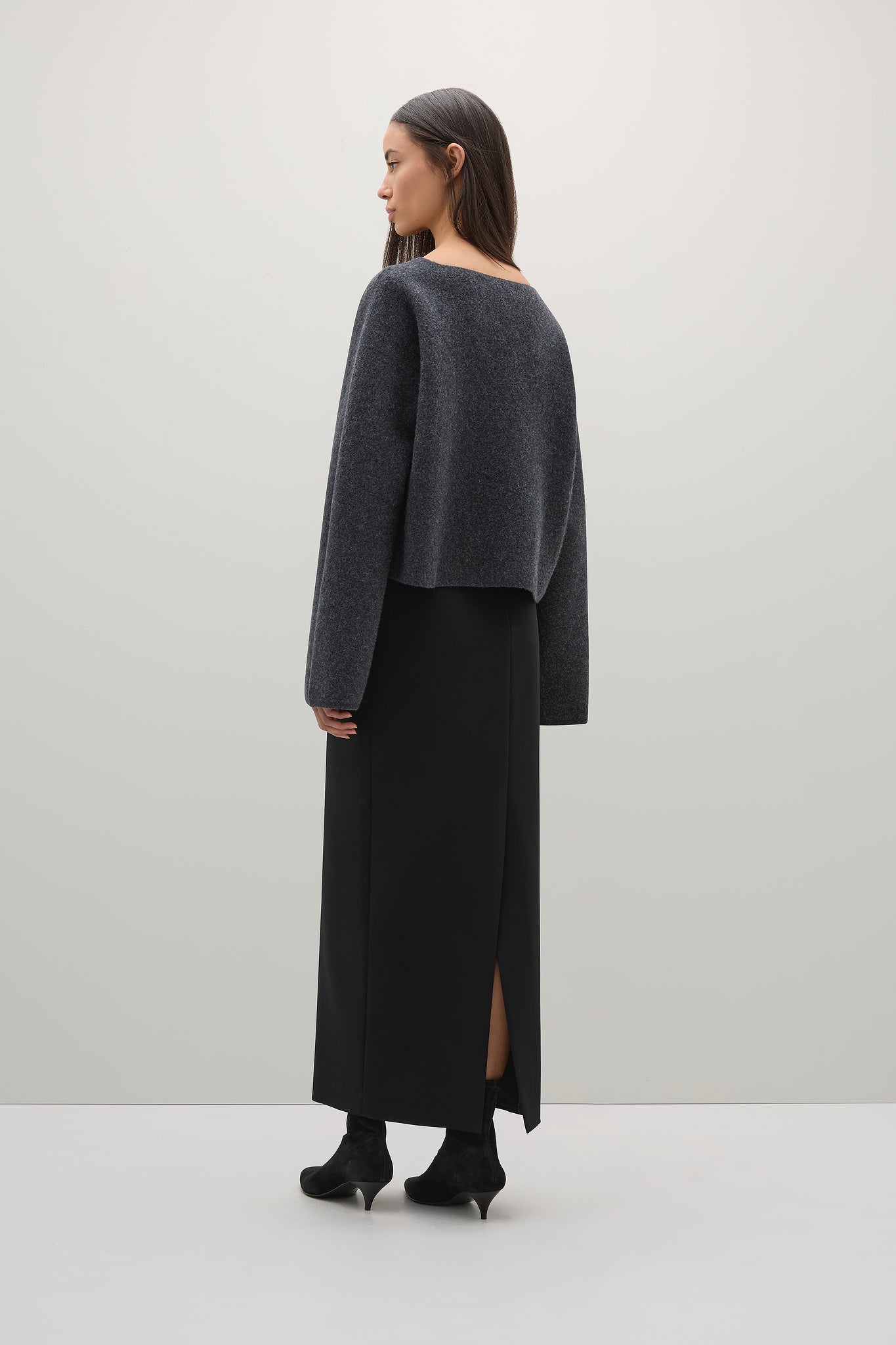 Woman wearing a dark gray sweater and black skirt on a white background