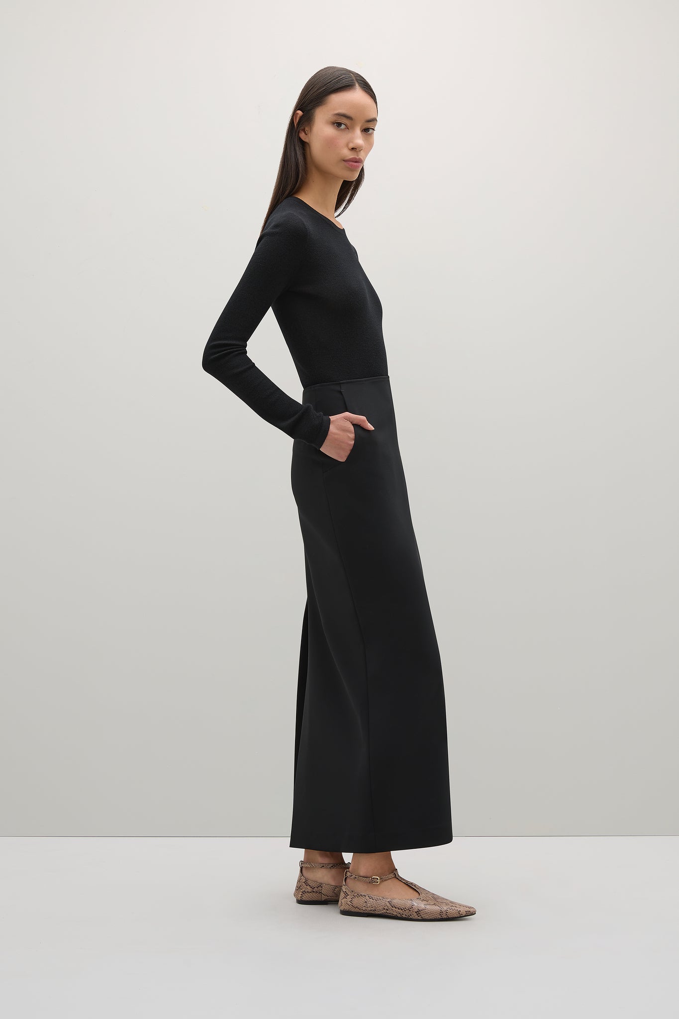 Woman wearing a long black dress against a white background