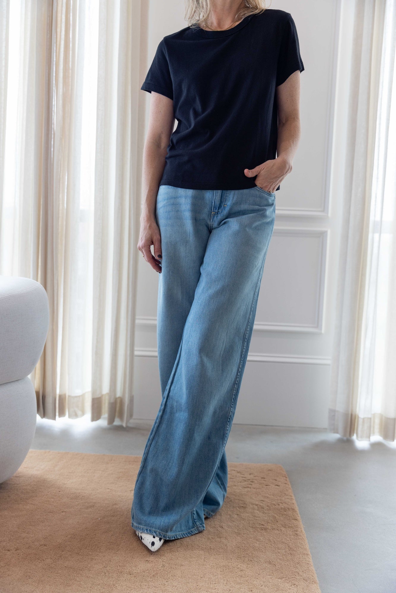 Woman wearing the lovey tee in black and the amo mid-rise wide leg jeans.