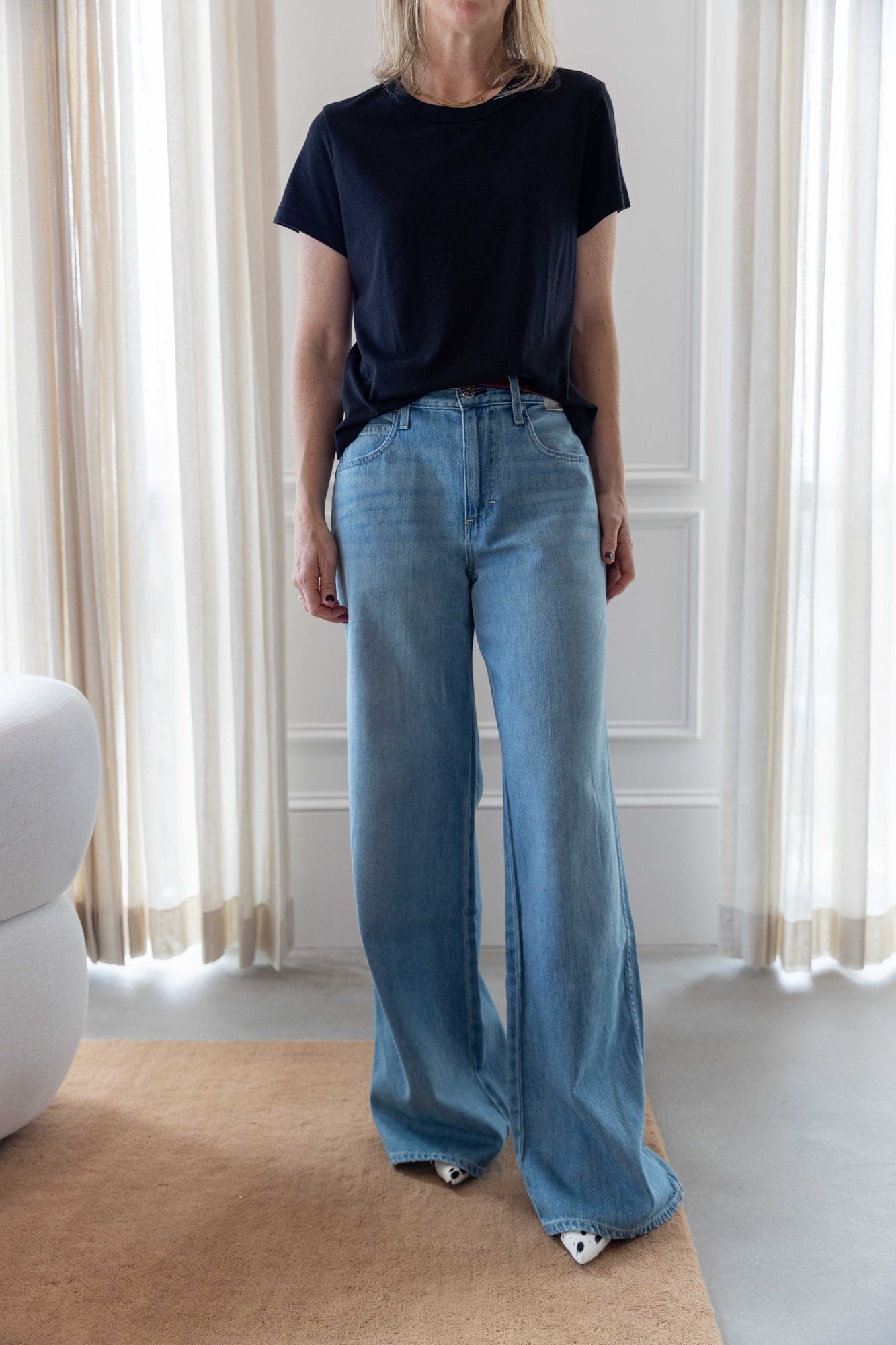 Woman wearing the lovey tee in black and the amo mid-rise wide leg jeans.