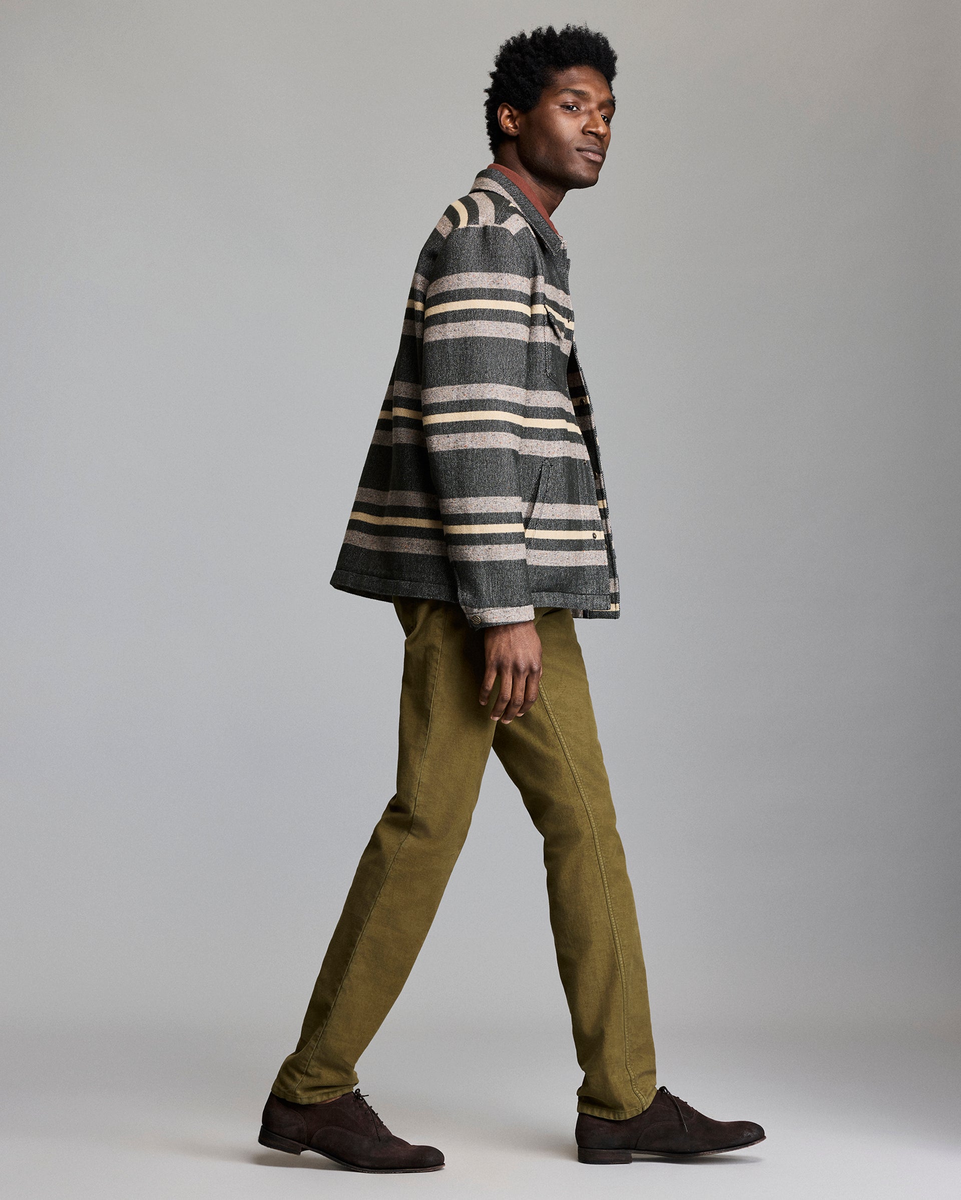 Man wearing a striped shirt and green pants against a plain background