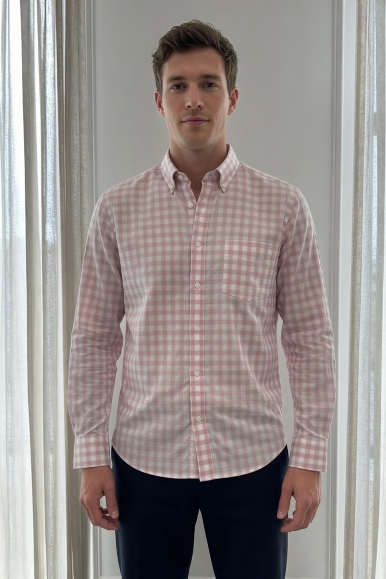 Man wearing a pink checkered shirt standing against a neutral background