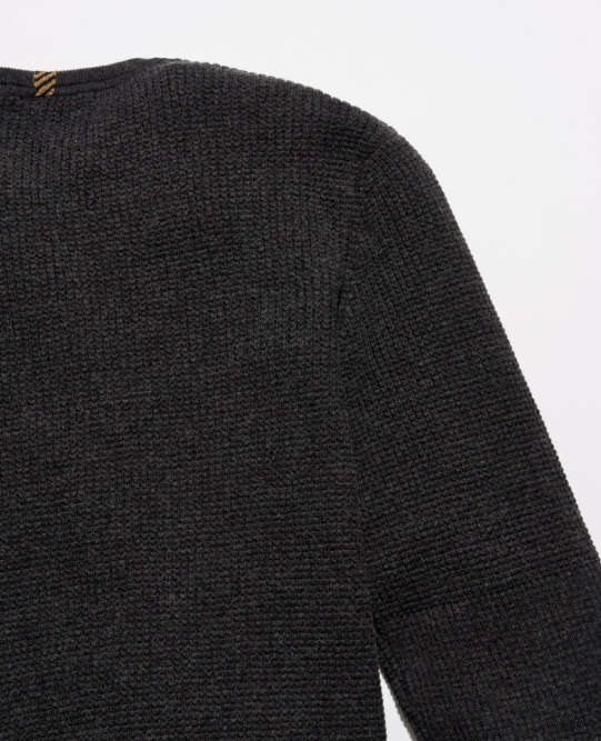 Close-up of a dark charcoal gray ribbed knit sweater showing the shoulder and sleeve texture against a plain white background.