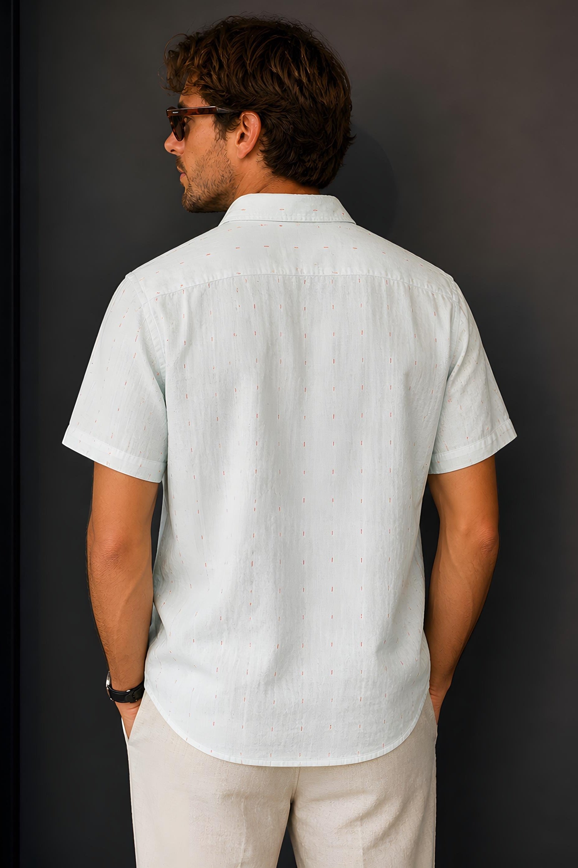 Backside of Man wearing a Billy Reid Short Sleeve Shirt in Herringbone Treme and sunglasses against a dark background
