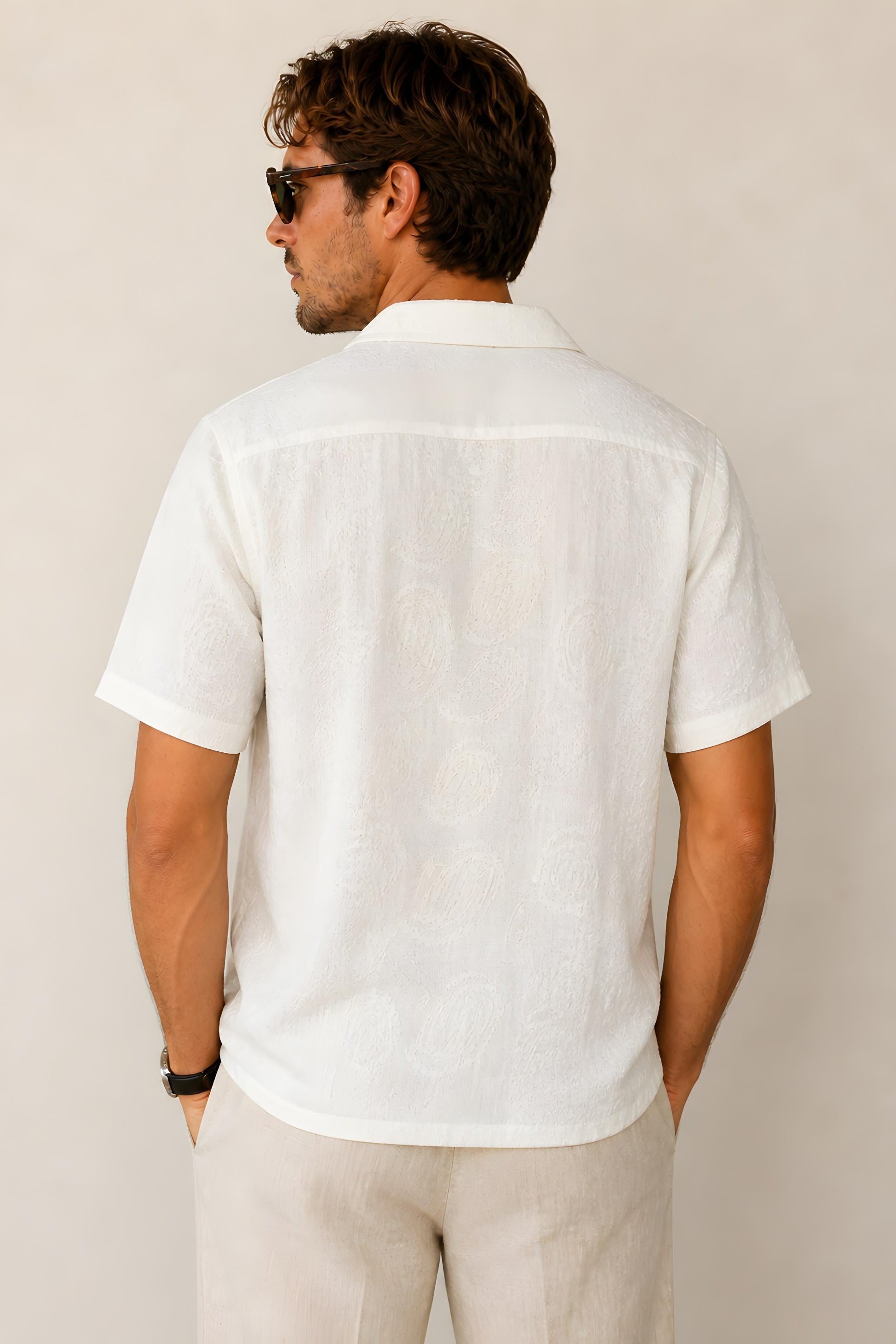 Backside of a man wearing a Billy Reid Short Sleeve Shirt Numajiri Beach Shirt in Tinted White and sunglasses against a plain background