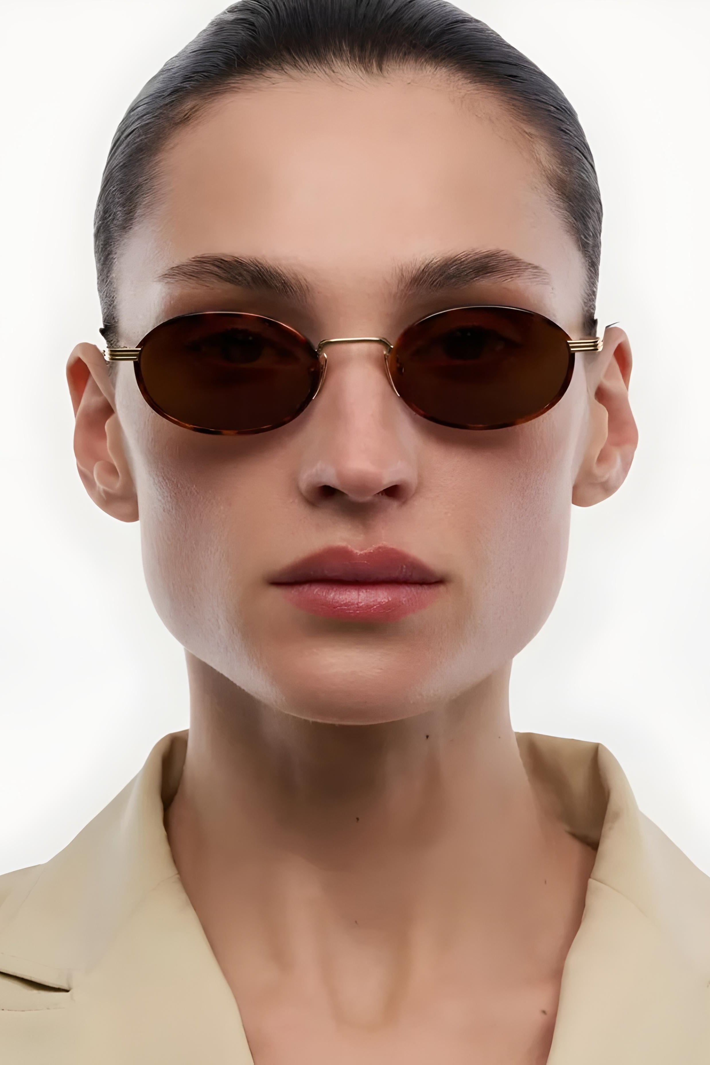 Person wearing brown oval sunglasses with a plain background