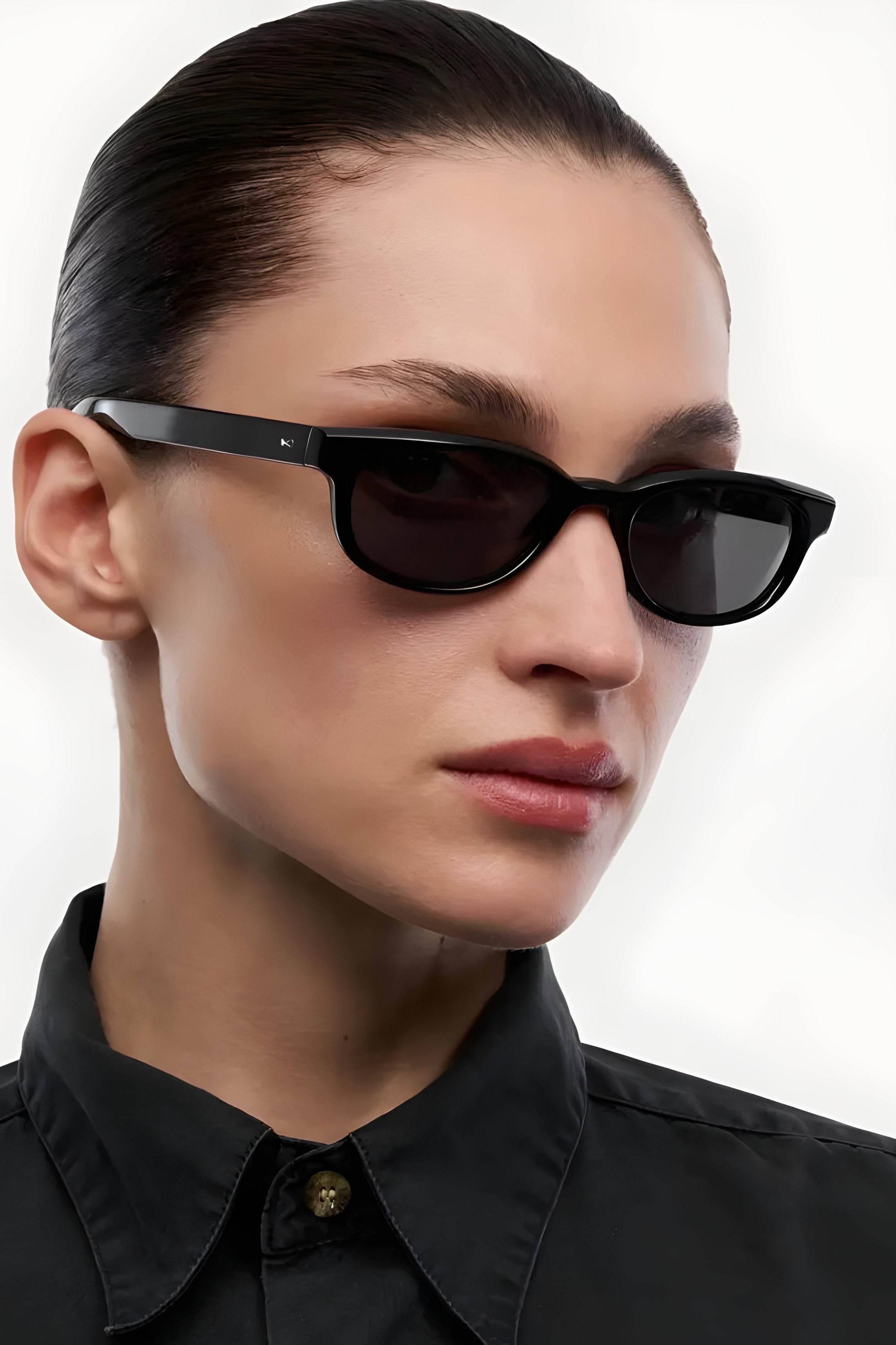 Person wearing black sunglasses with a plain background