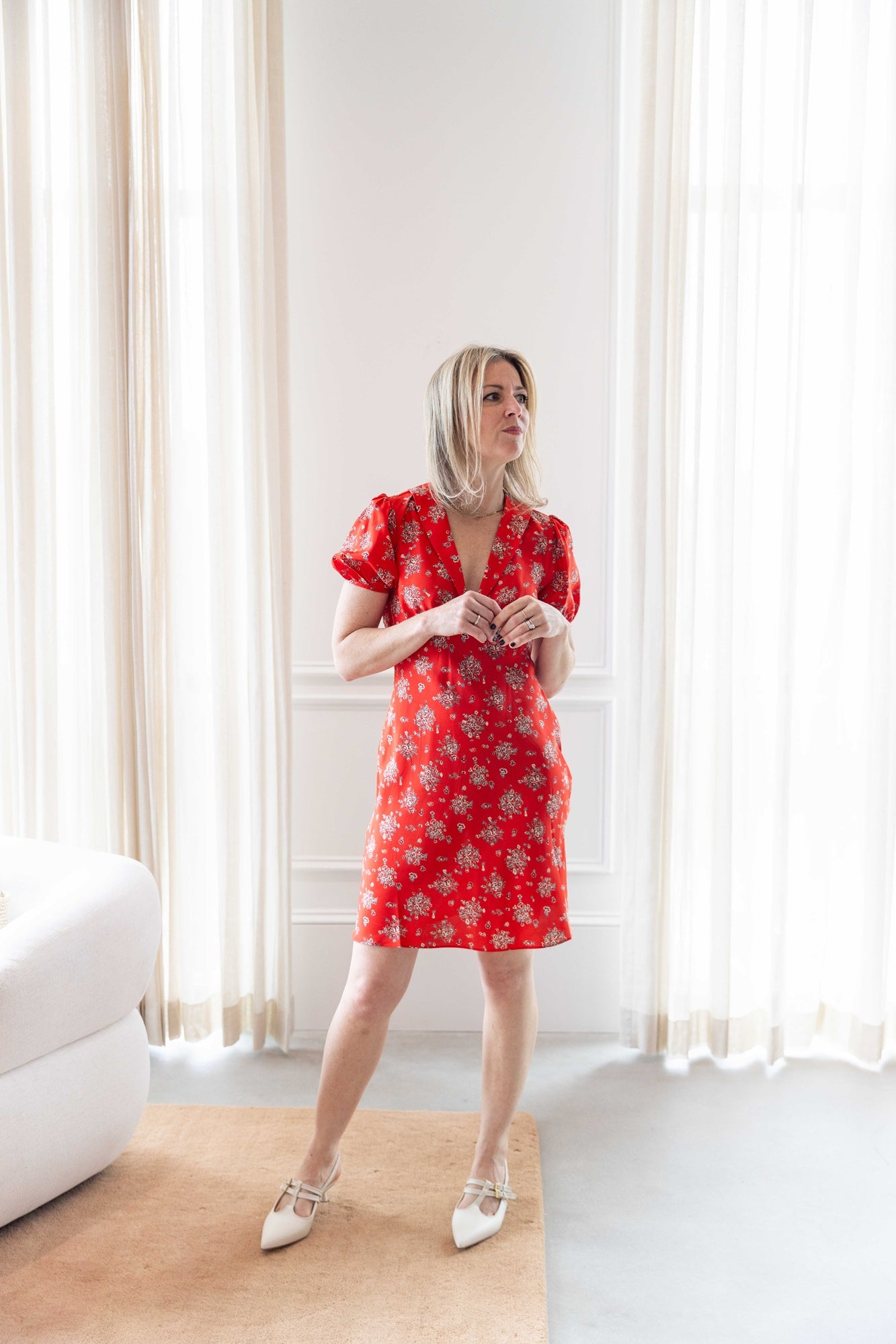 Woman wearing ciao lucia alix dress standing in a room with white curtains.