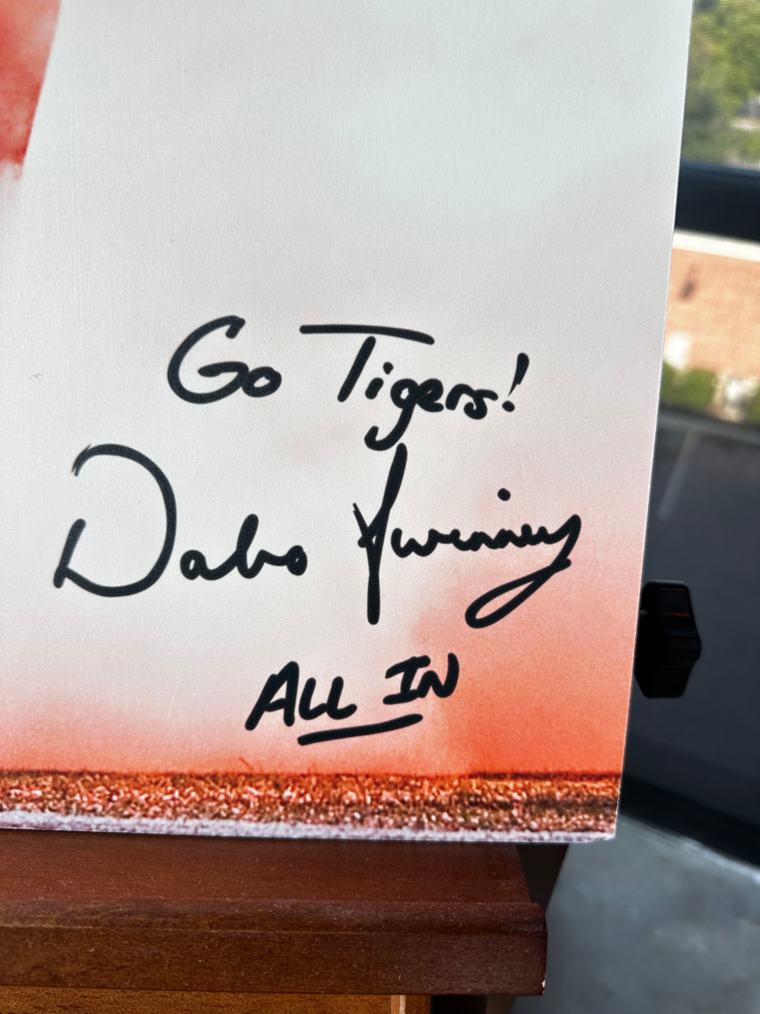A close-up of a custom canvas print featuring a sunset gradient design with the handwritten text 'Go Tigers! Dabo Swinney All In' in black marker, resting on a wooden surface.