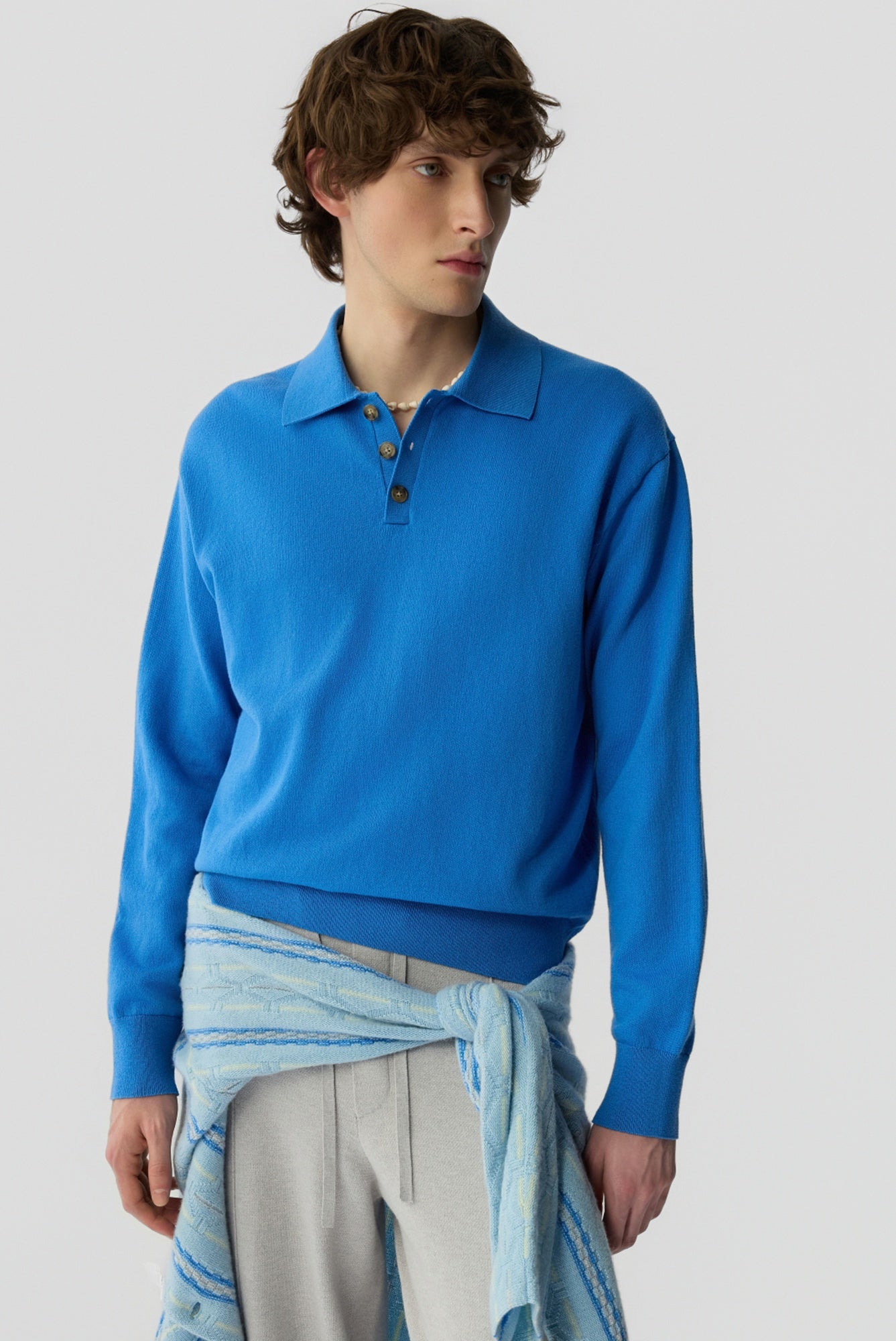 Person wearing a blue long-sleeve shirt with a plain background