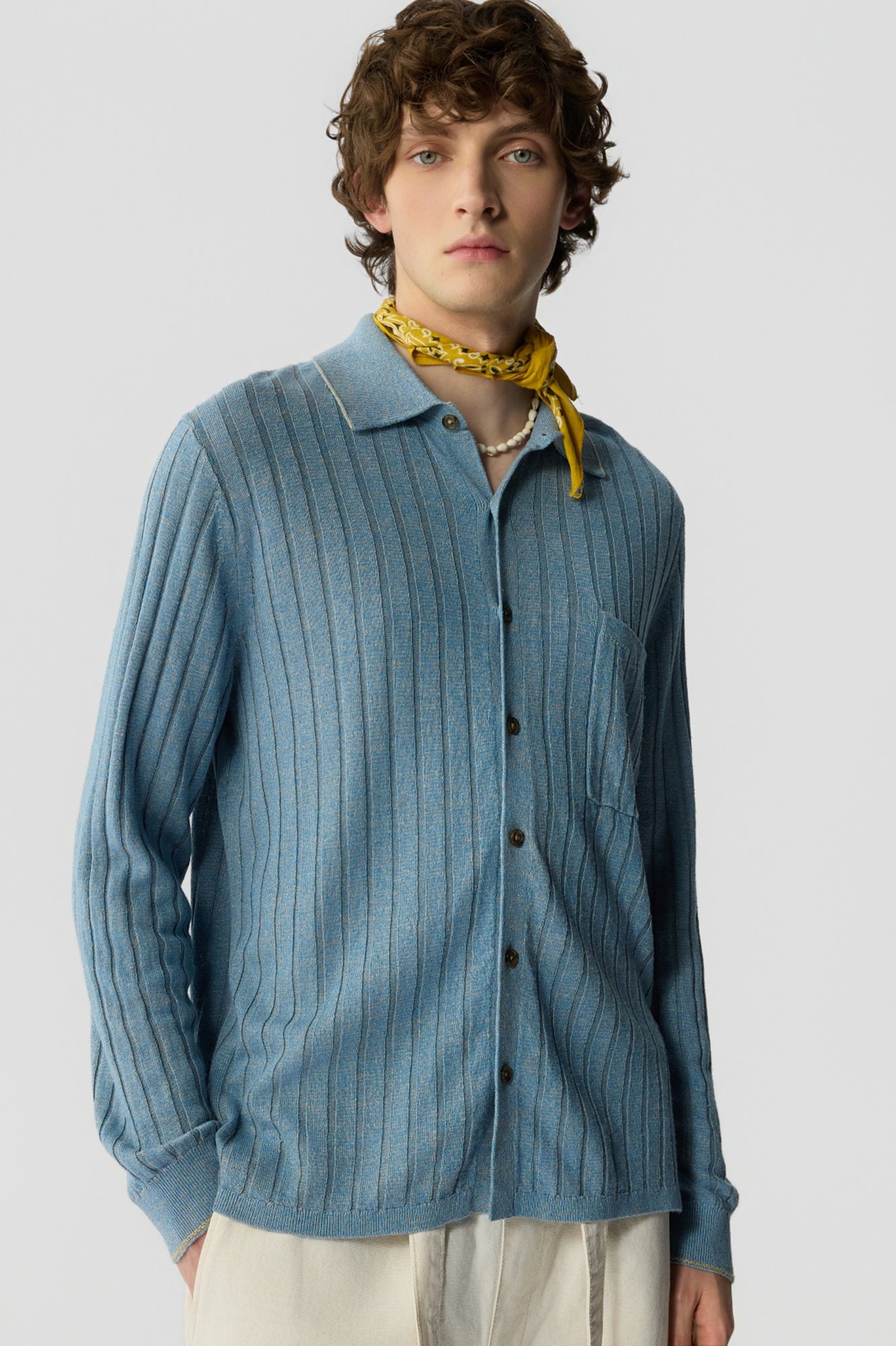 Man wearing a blue striped shirt with a yellow bandana around his neck on a light gray background