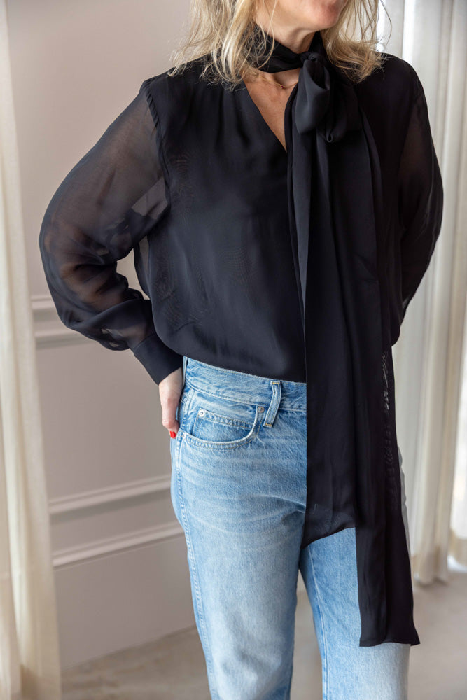 Dagmar Chiffon Scarf Blouse in black viscose, worn three-quarter view with sheer sleeves and light-wash denim