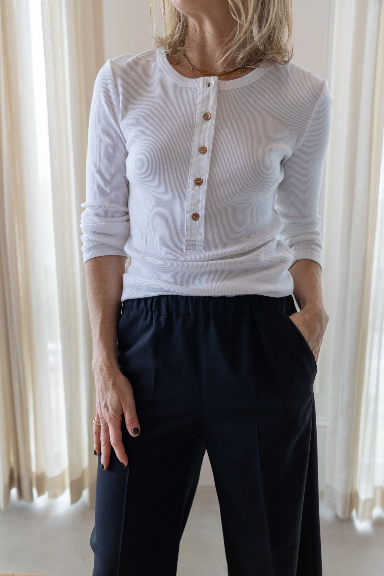 Close up of a woman wearing a house of dagmar henley top in white and house of dagmar elastic trouser.