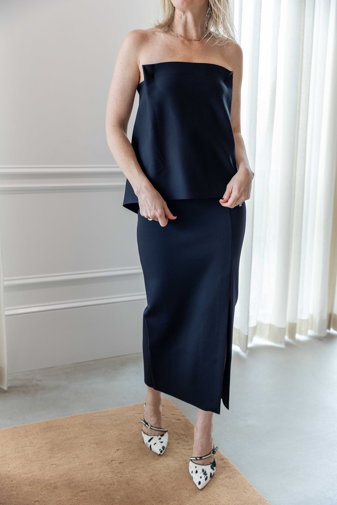 Woman wearing the house of dagmar fitted midi skirt and house of dagmar square tube top standing in a room with white curtains and a tan area rug.