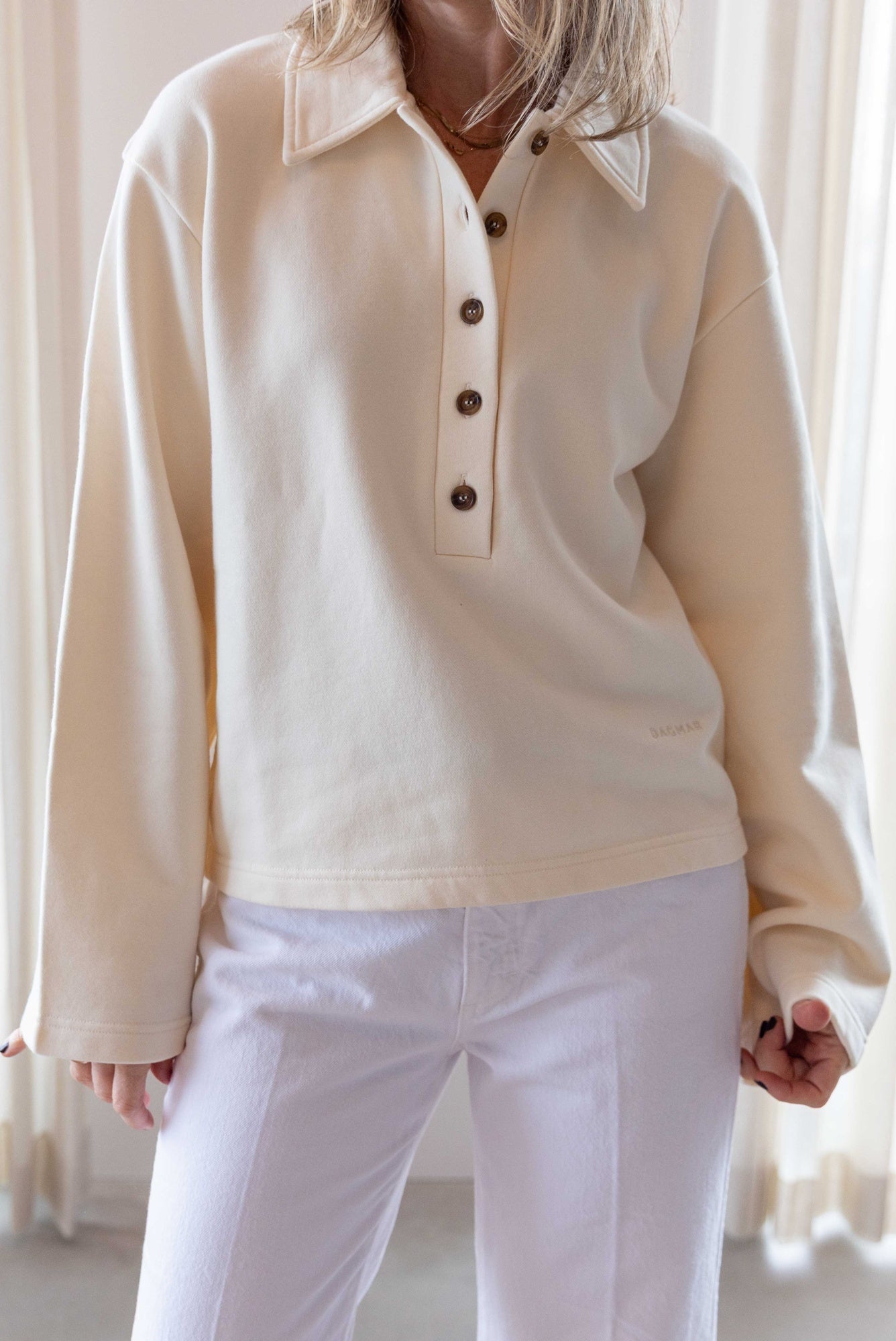 Close up image of a woman wearing the house of dagmar polo sweatshirt and the amo denim robbie mid-rise relaxed jean.