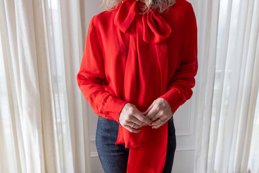 Dagmar Chiffon Scarf Blouse in red viscose, worn front view with the scarf tie falling over dark denim