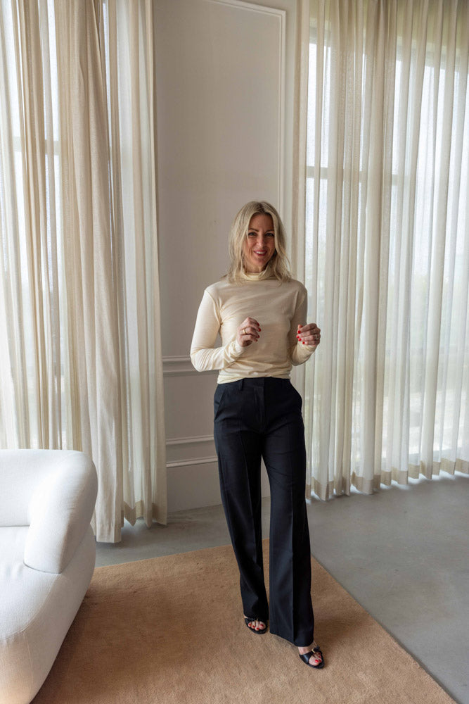 Dagmar Classic Suit Trouser in black wool blend, worn full length with a cream rollneck top and strappy heels
