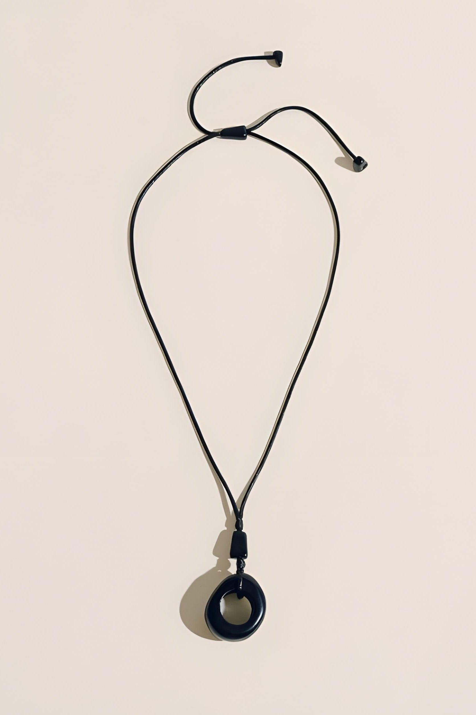 Black necklace with a pendant on a beige background