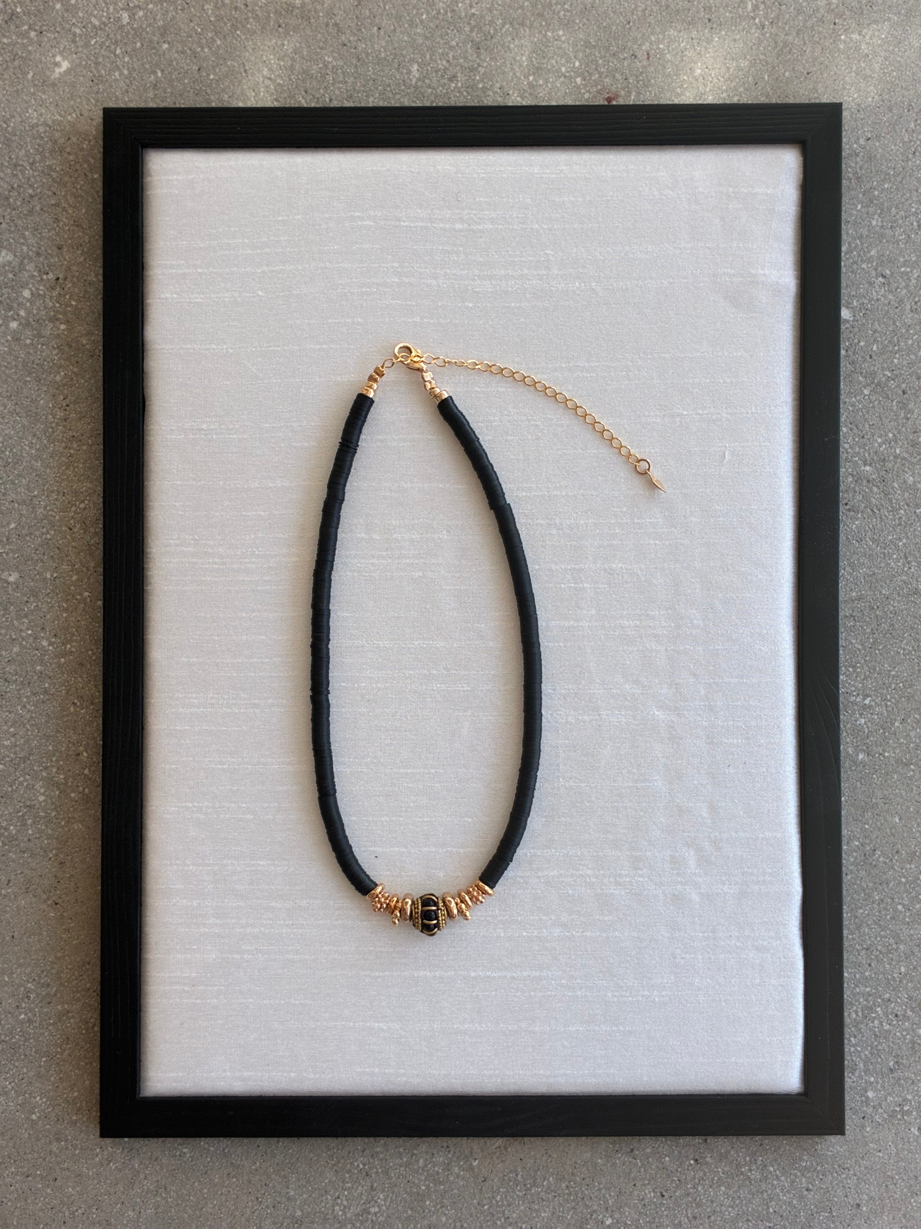 Gachon Pothier Puka Bakelite beaded necklace with black beads and 18kt gold plated hardware on a light gray background.