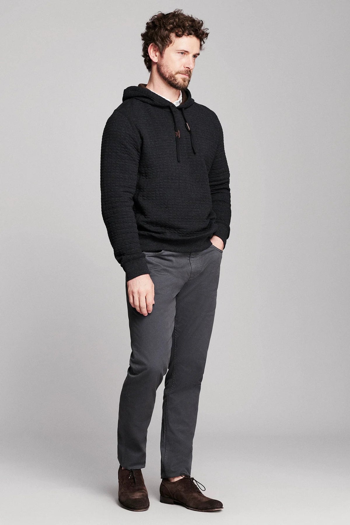 Billy Reid Box Quilt Hoodie Pullover in black quilted cotton jacquard, worn three-quarter view with charcoal trousers