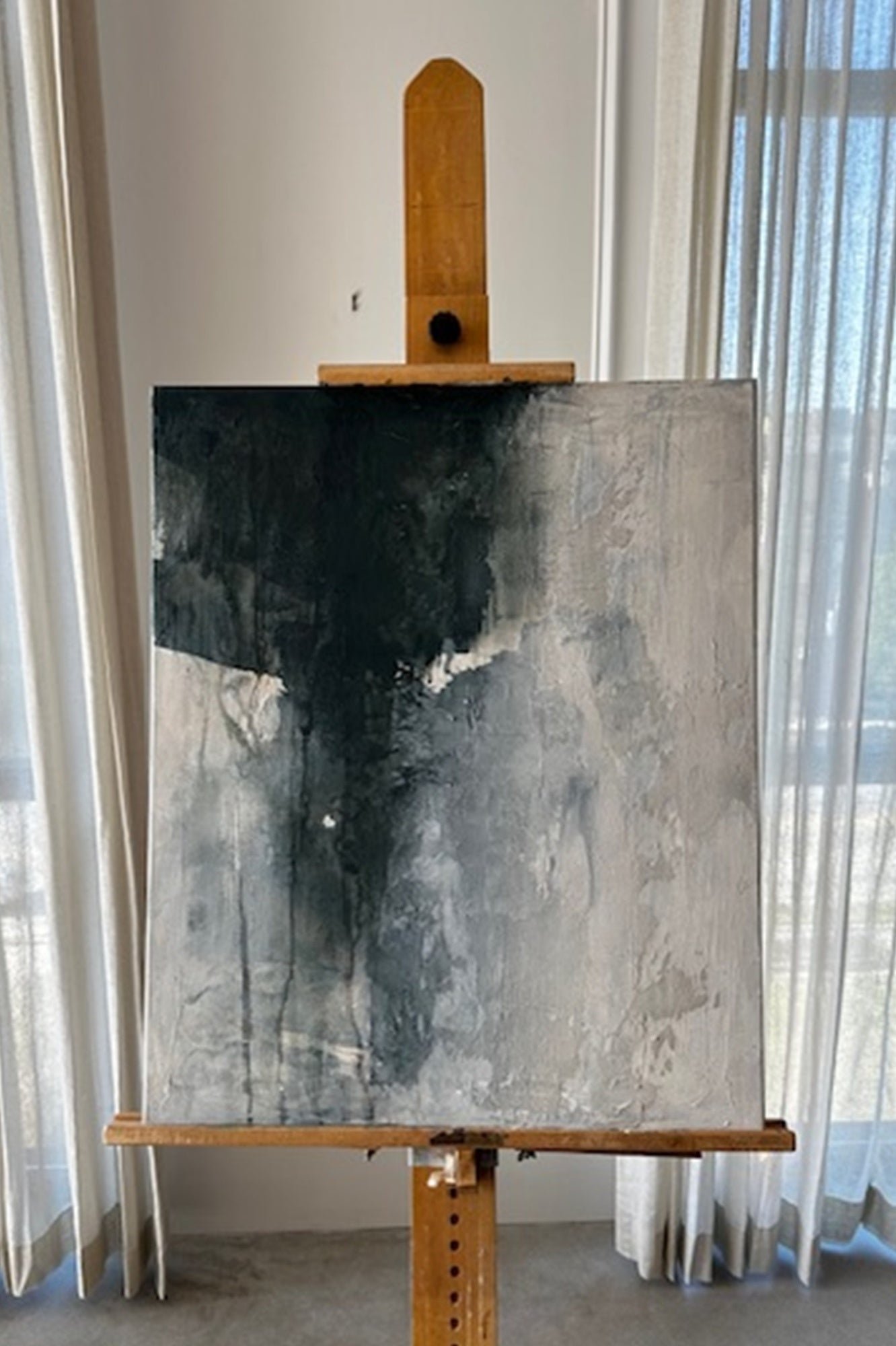 Abstract painting on an easel against a white wall