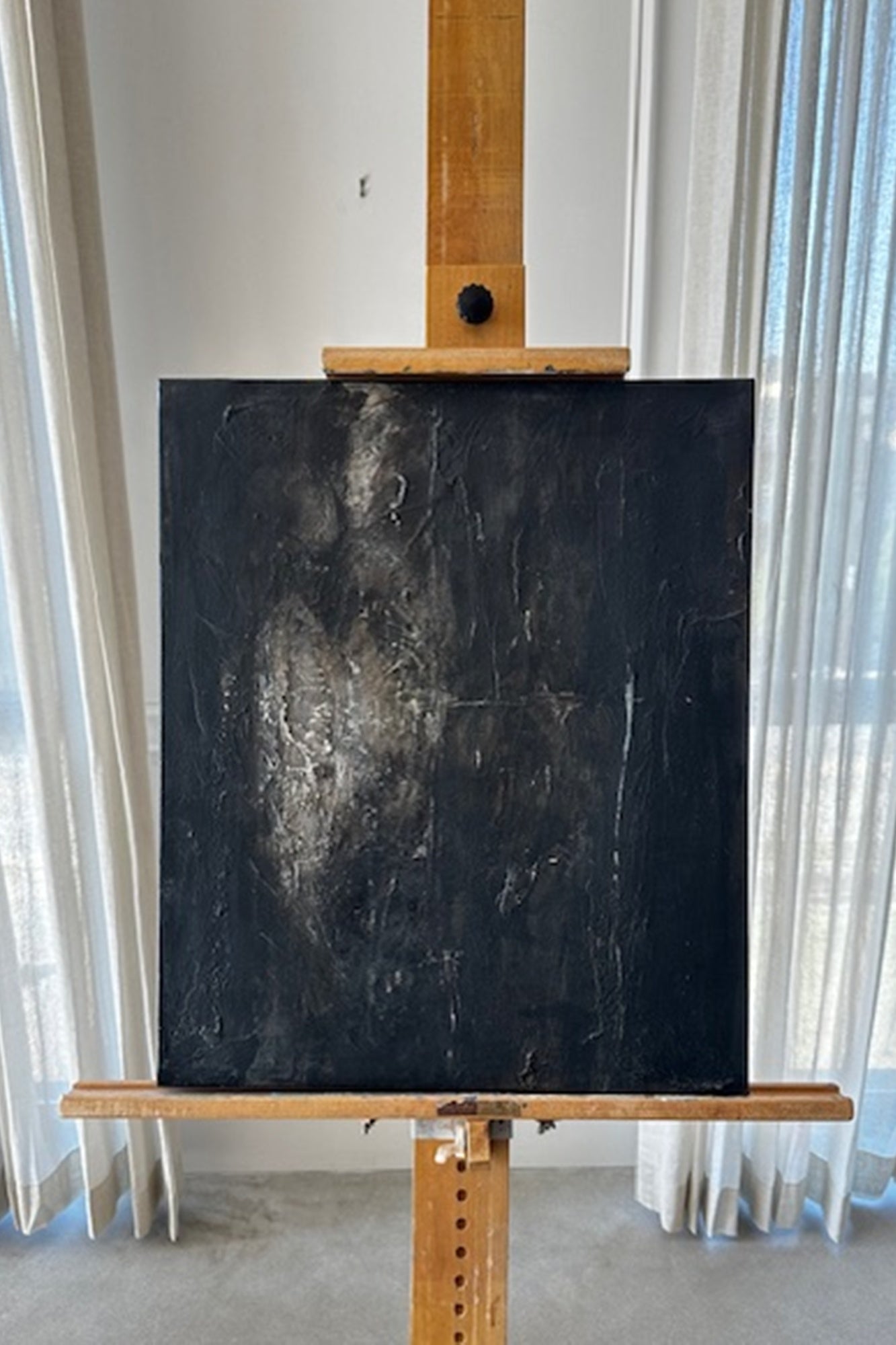Wooden easel with a large blackboard against a white curtain backdrop