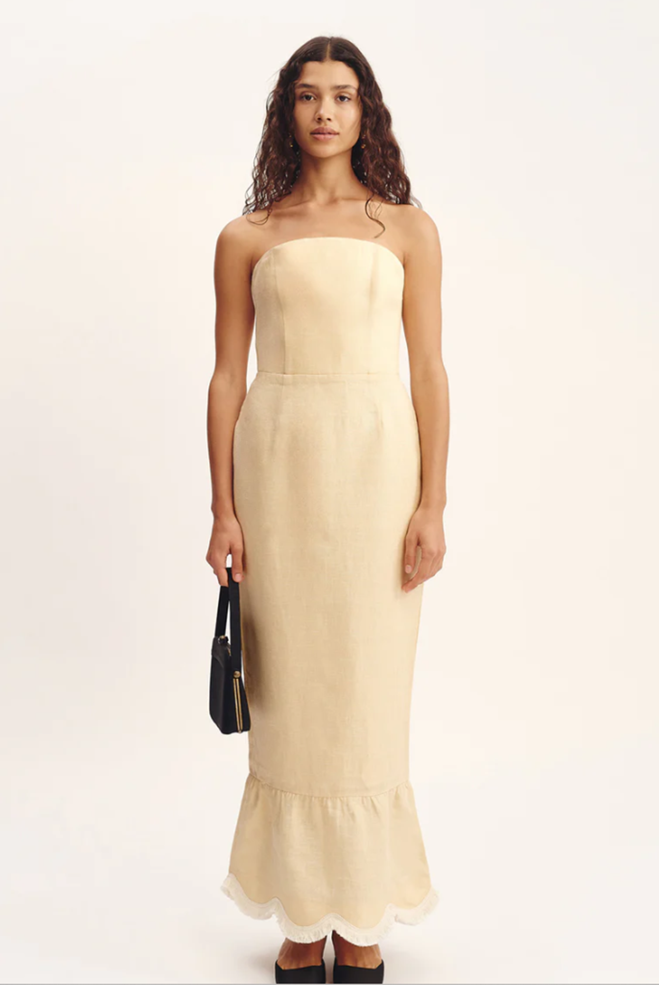 Woman wearing a beige strapless dress with a plain background
