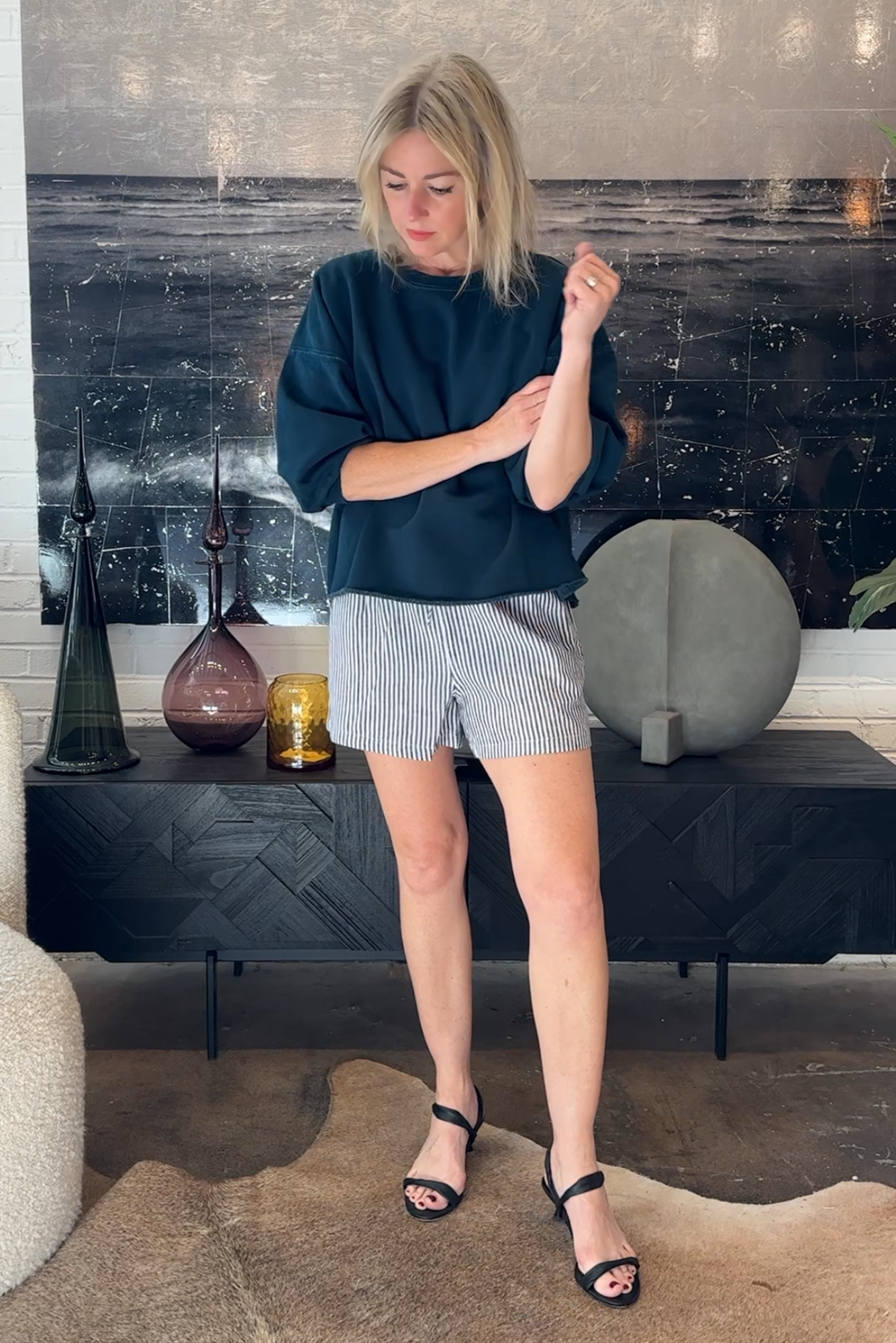 Woman in a room with decorative vases and a textured wall.