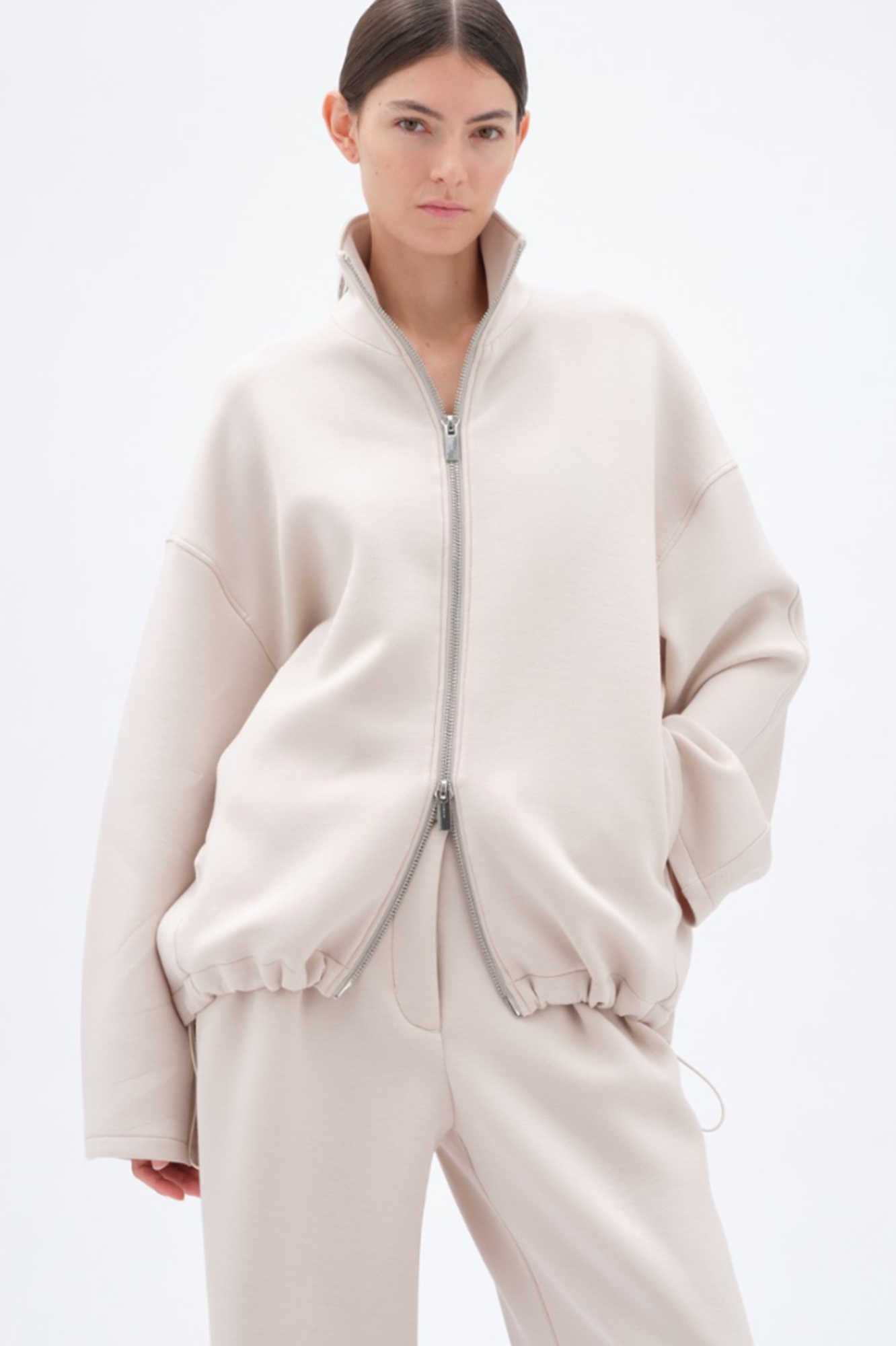 Person wearing a beige soft jacket on a white background