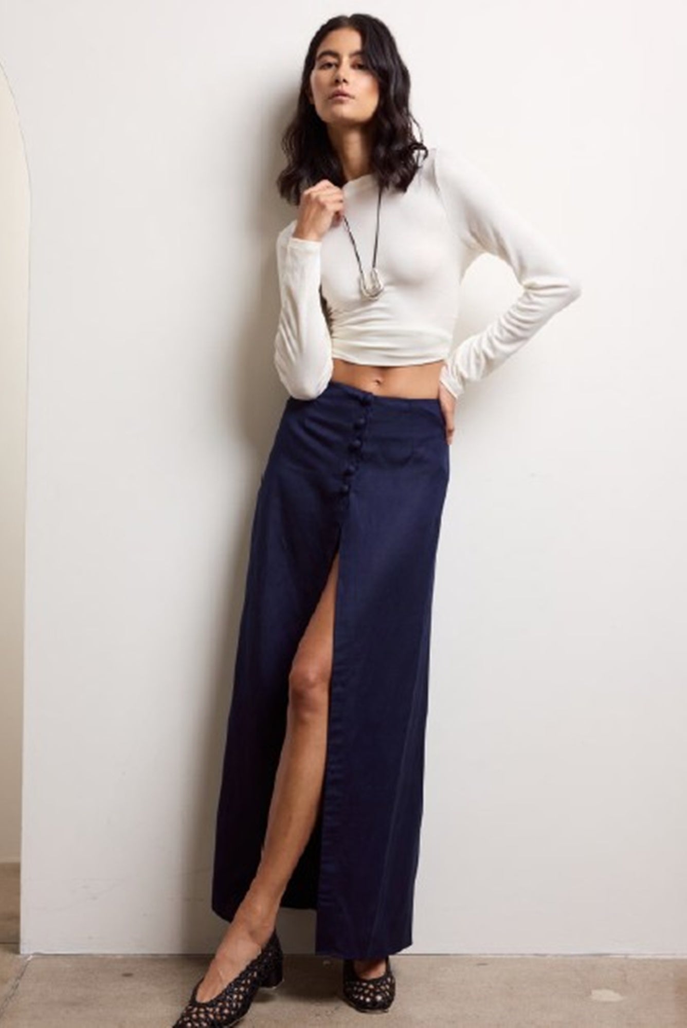 Woman wearing the onia high slit maxi skirt standing against a white wall