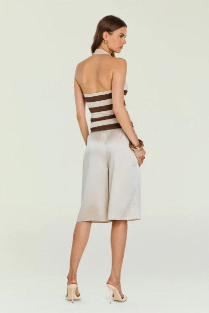 Backside of a woman wearing the seroya amira tank with long shorts in front of a cream background