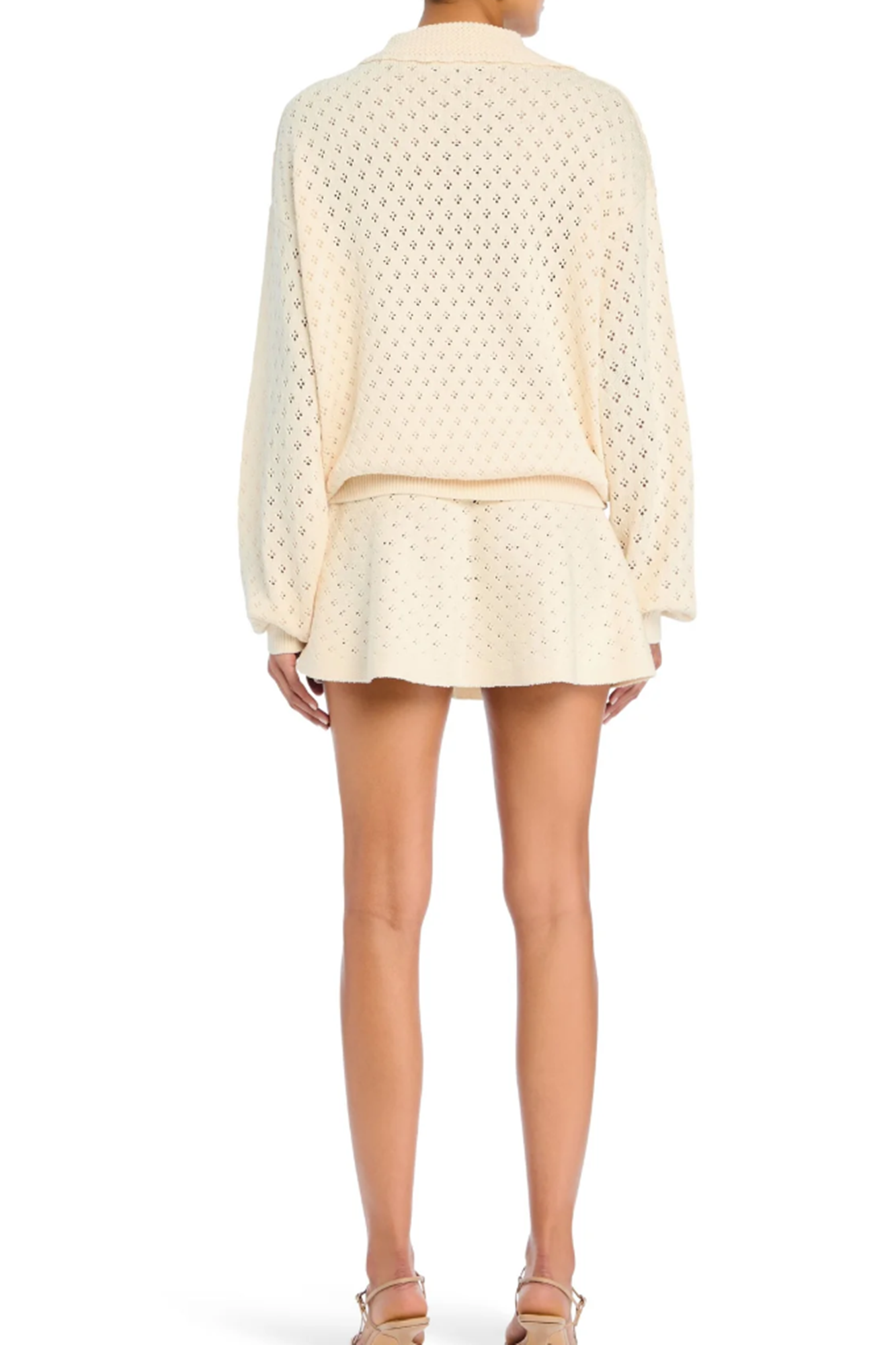 Person wearing a cream-colored textured top and skirt set on a white background