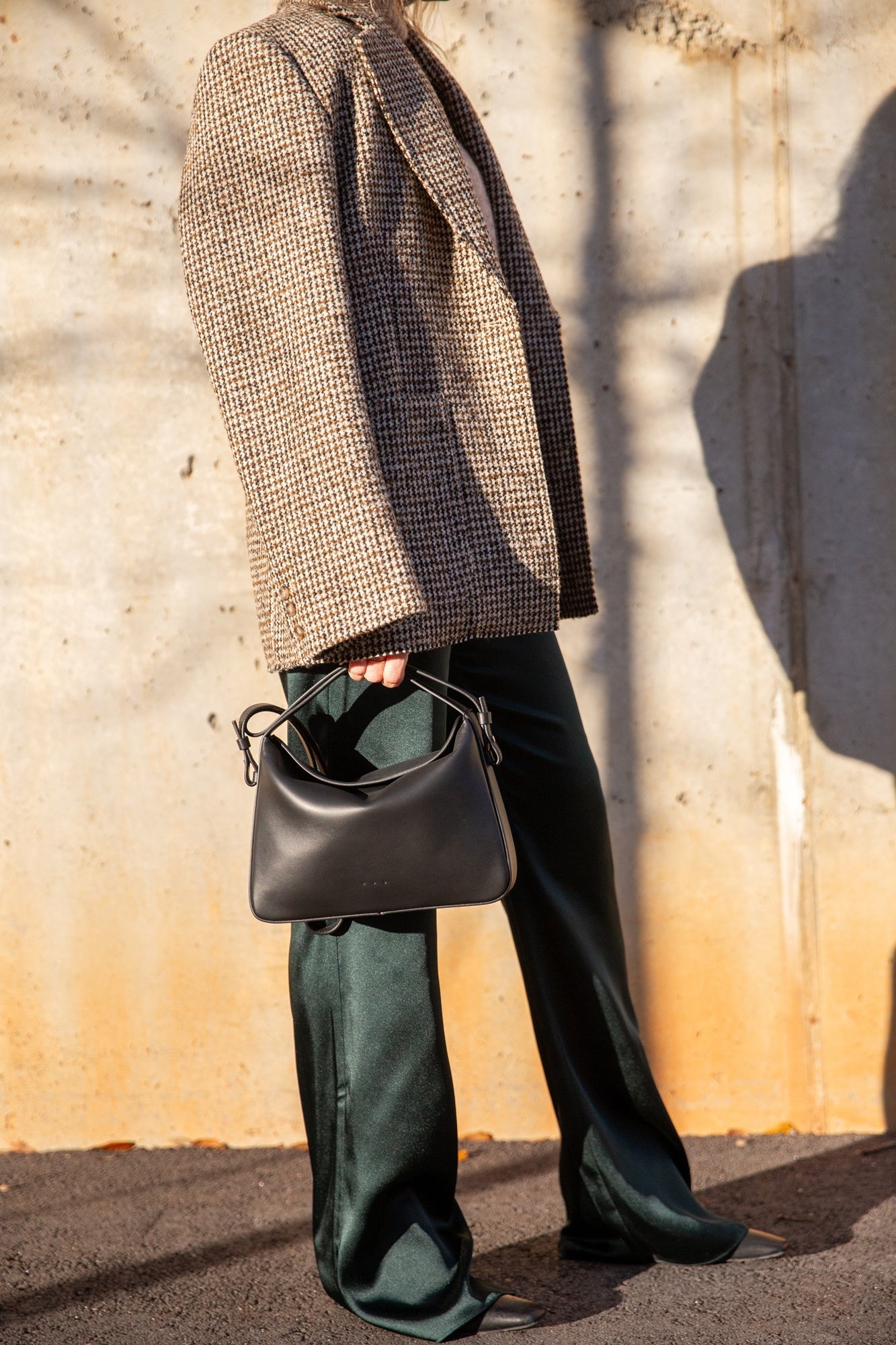 image of a model wearing the House of Dagmar Coat, Aesther Ekme Handbag and Seroya Viva Satin Pants