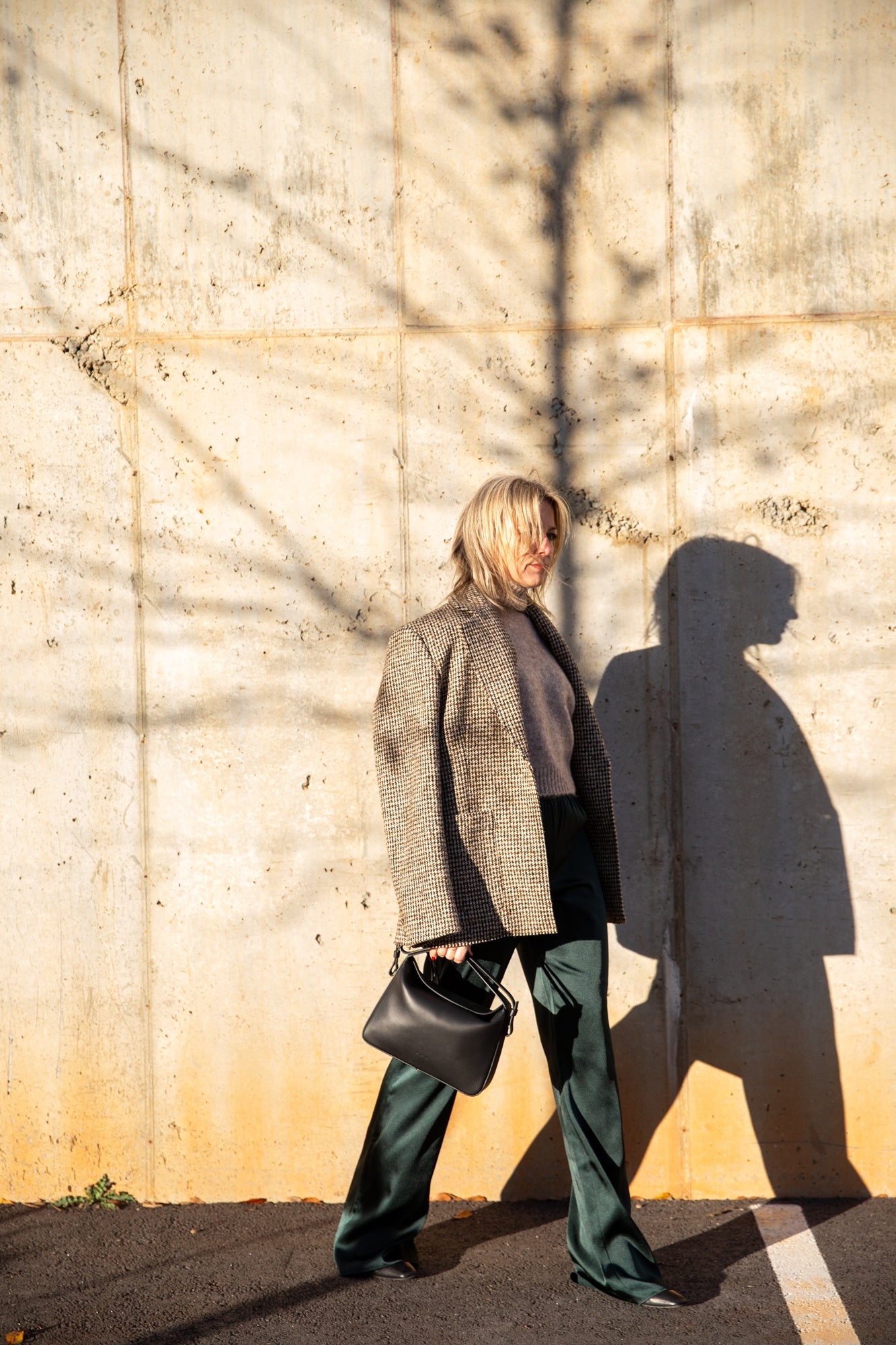 image of a woman wearing the House of Dagmar Tweed Coat, Seroya Viva Satin Pants and Tahara Sweater with the Aesther Ekme Handbag