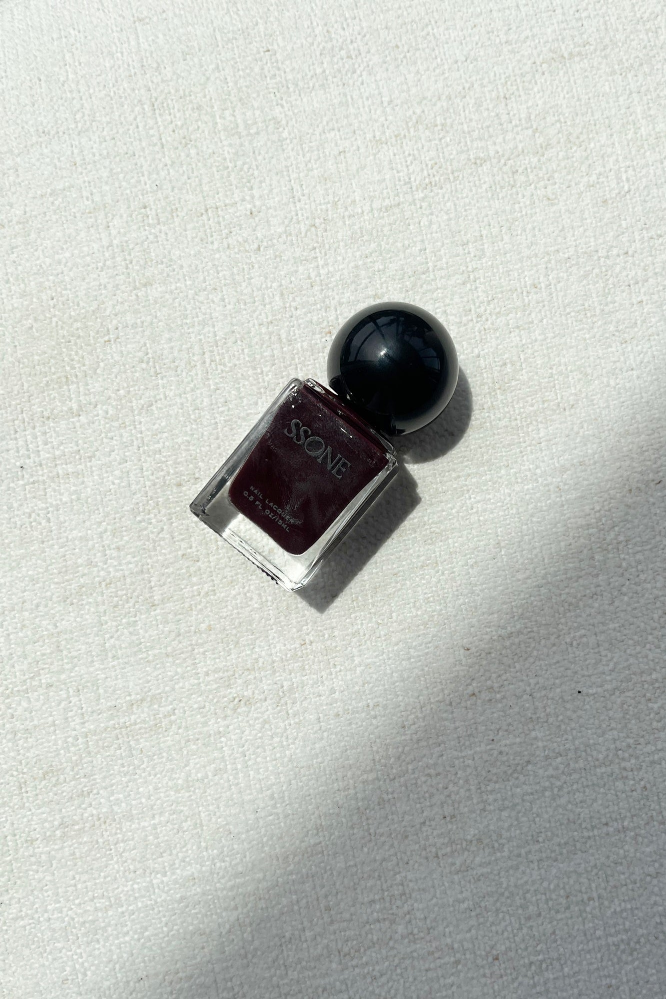 Ssone Odessa Nail Polish lbottle aying on a white couch