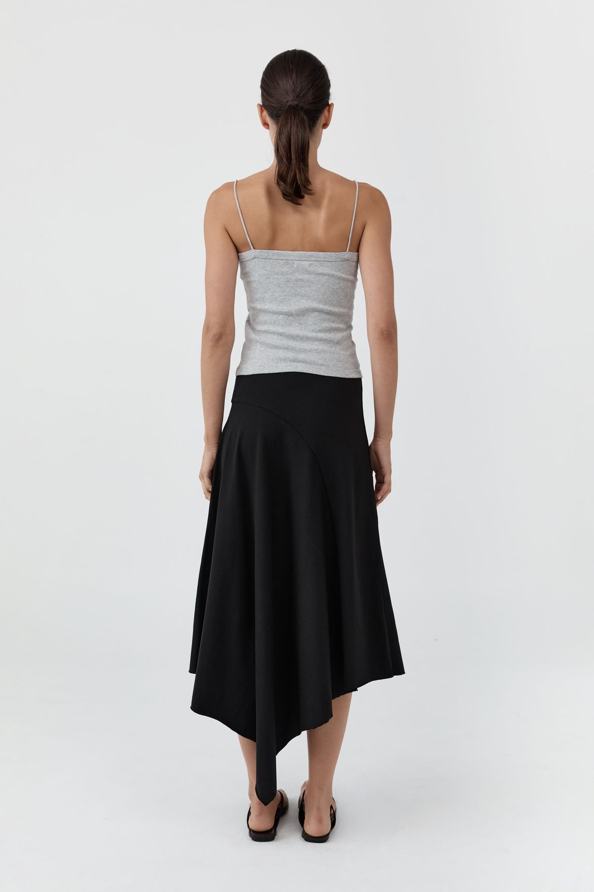 Woman wearing a gray top and black skirt on a white background