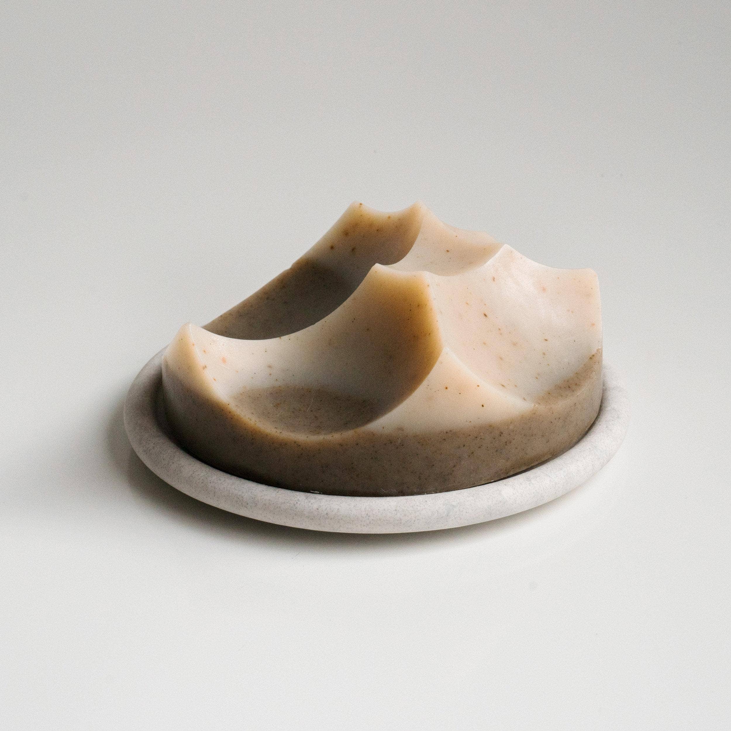 Bar of soap on a white plate with a plain background