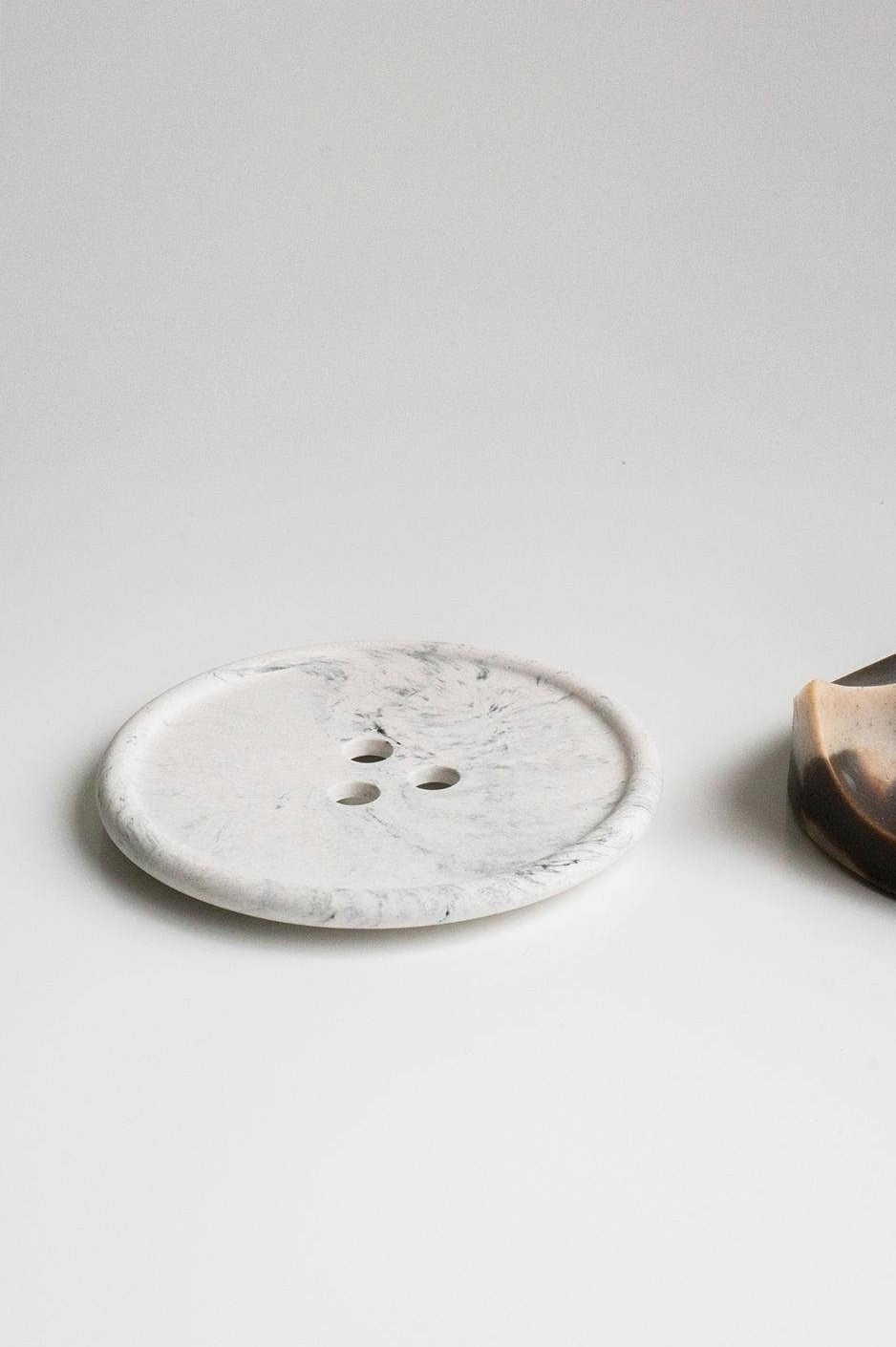Two ceramic items, one round and one half-moon shape, on a light gray background