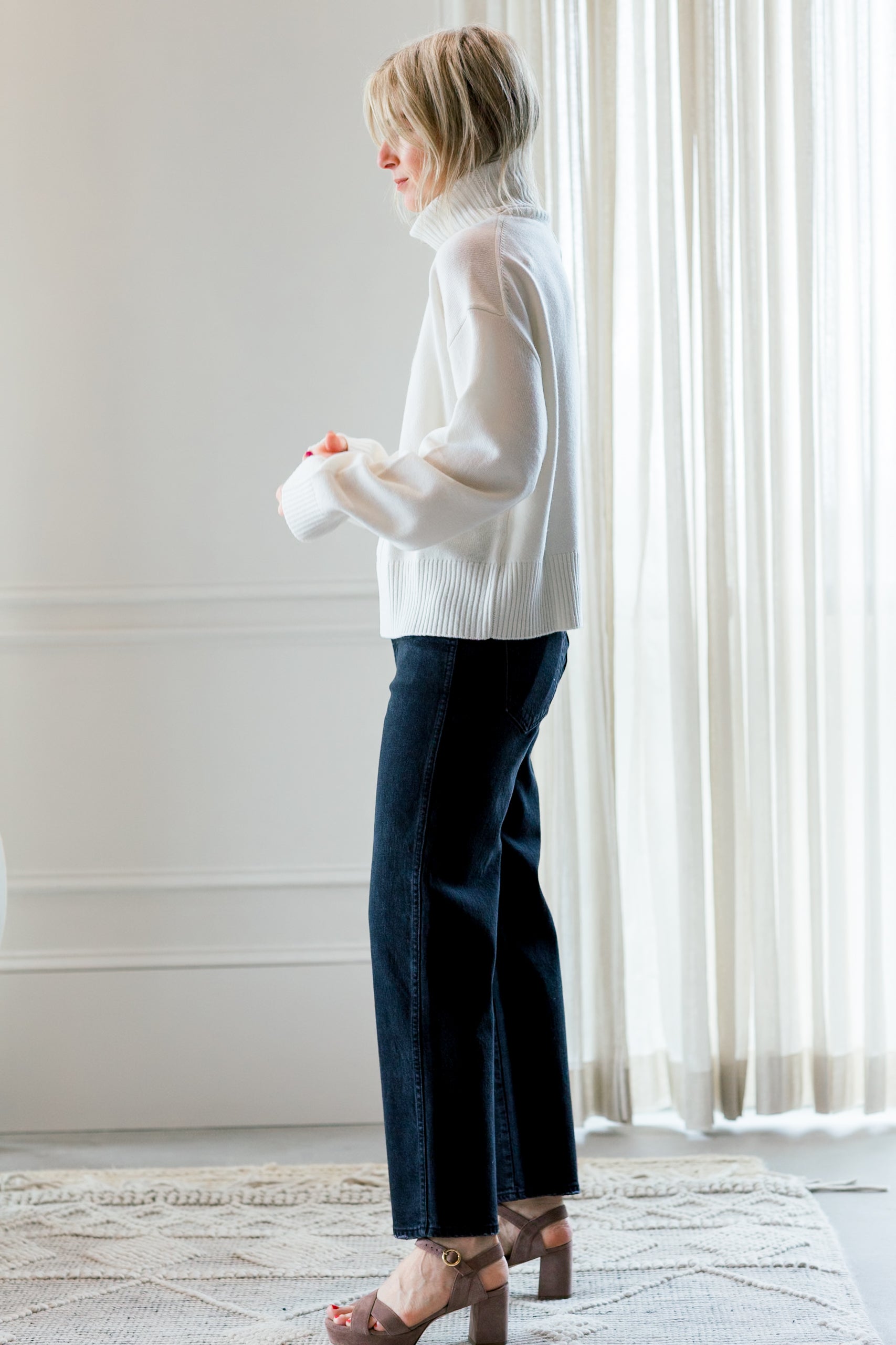image of a woman wearing the allude turtleneck sweater and amo billie jeans