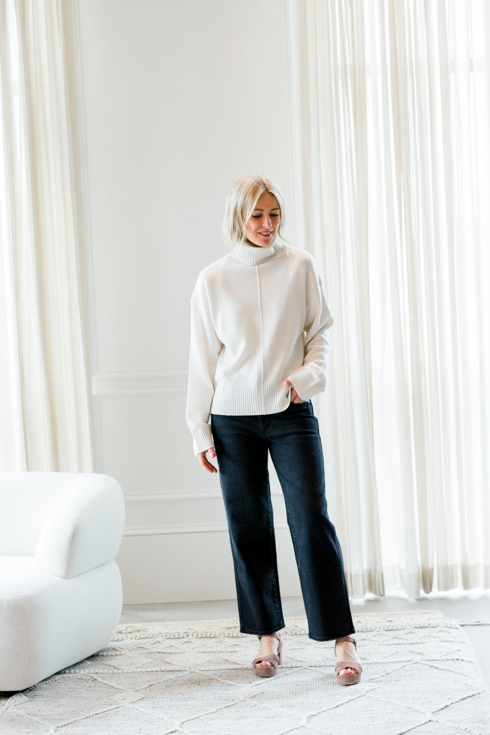 image of a woman wearing the allude turtleneck sweater and amo billie jeans